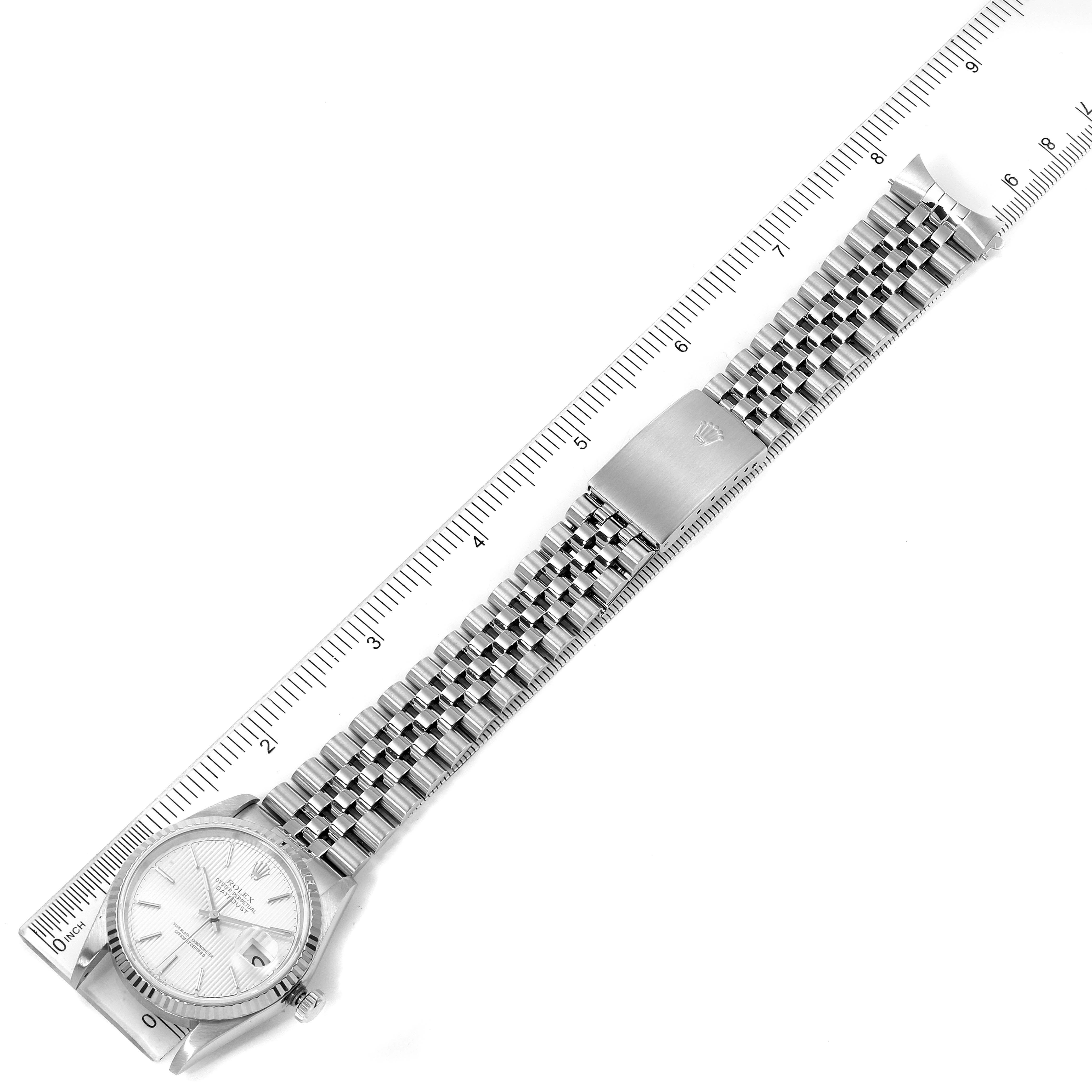 The Rolex Datejust 16234 Men
s Stainless Steel Silver Dial 16234 Men
s Stainless Steel Silver Dial watch is shown from a top-down angle, featuring its face, bracelet, and clasp laid flat against a ruler.