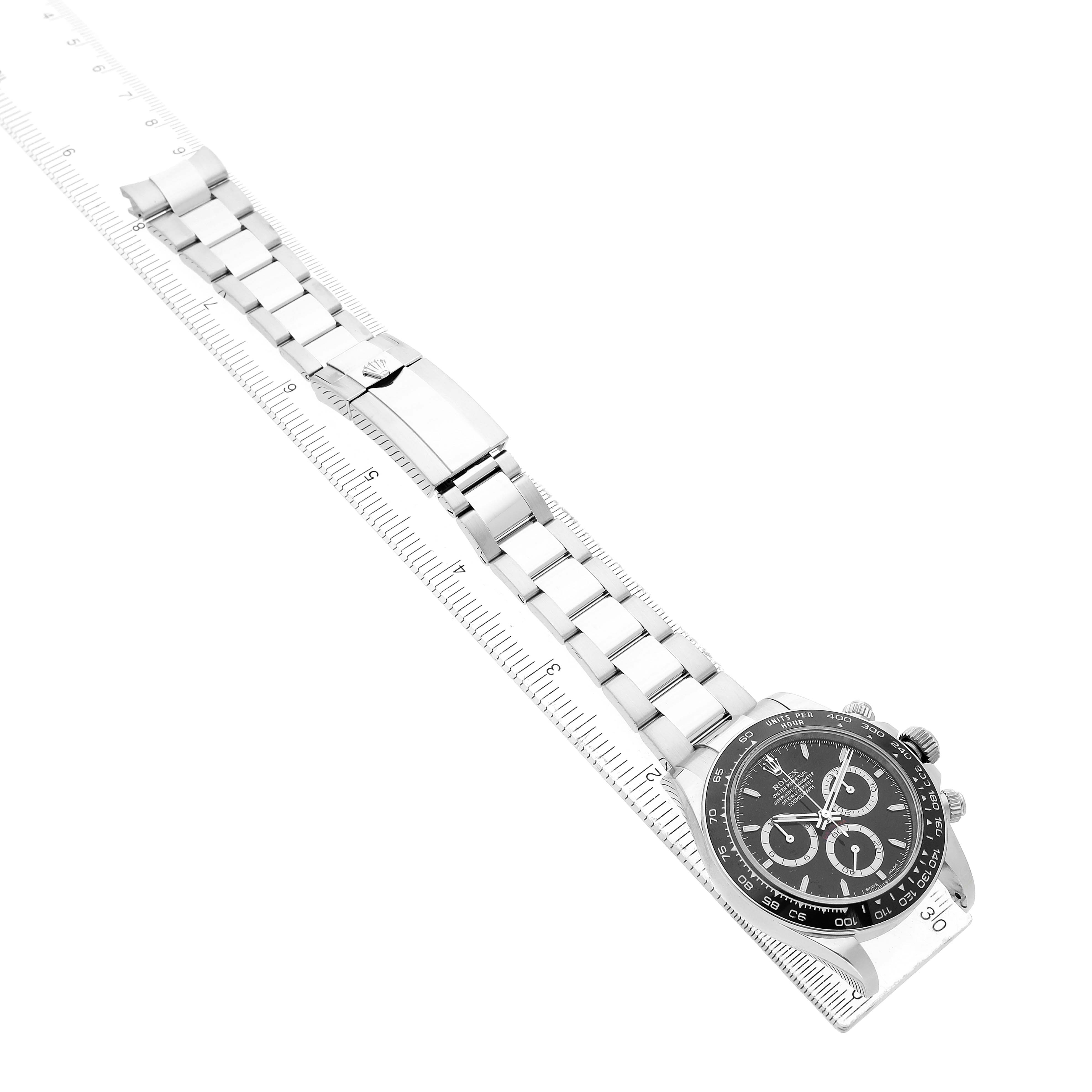 The image shows a Rolex Daytona 126500 Men's Stainless Steel Black Dial watch at an angle, featuring the full bracelet, clasp, and face with visible subdials.