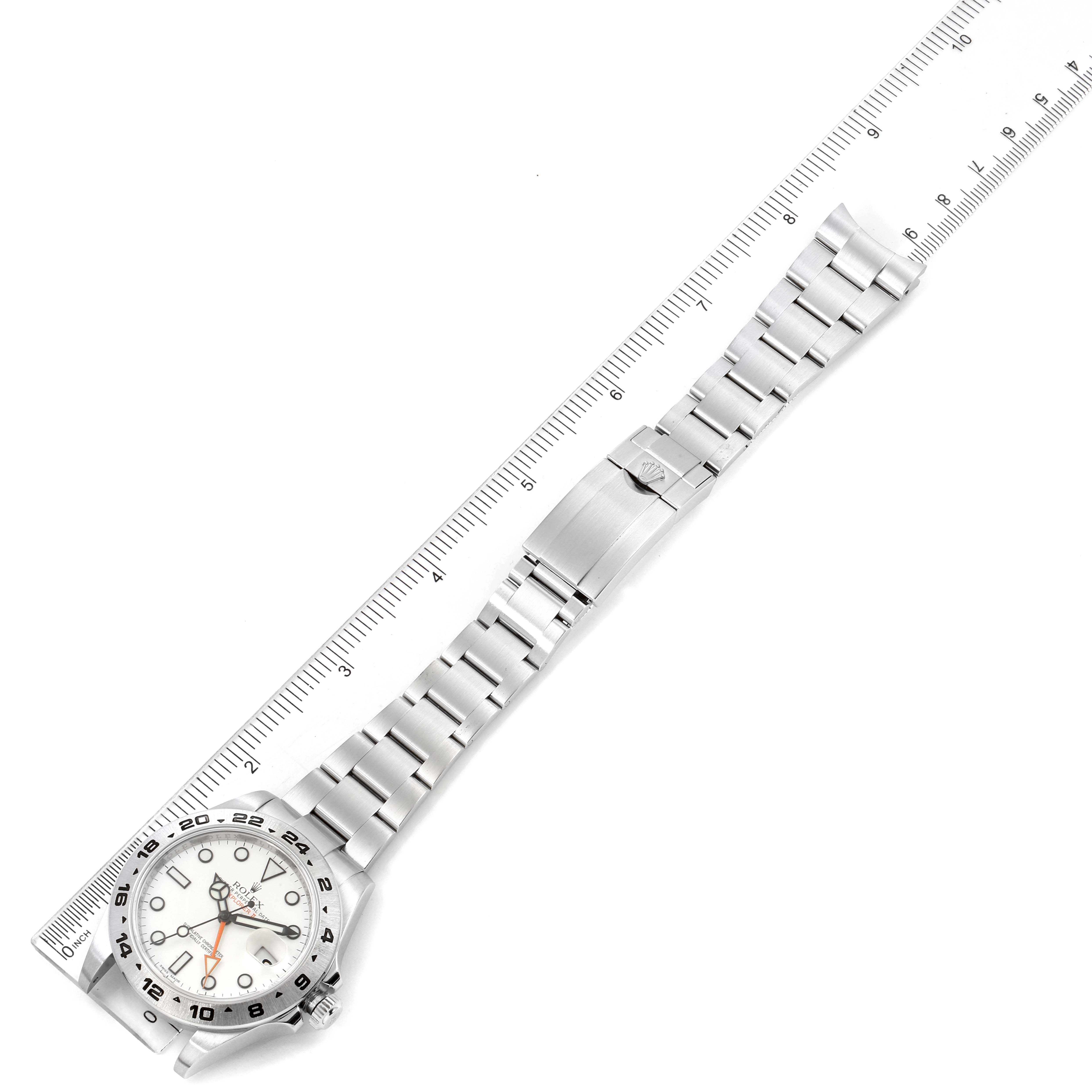 The image shows a top-down view of a Rolex Explorer 216570 Men's Stainless Steel White Dial 216570 Men's Stainless Steel White Dial watch with a linked metal bracelet next to a ruler.