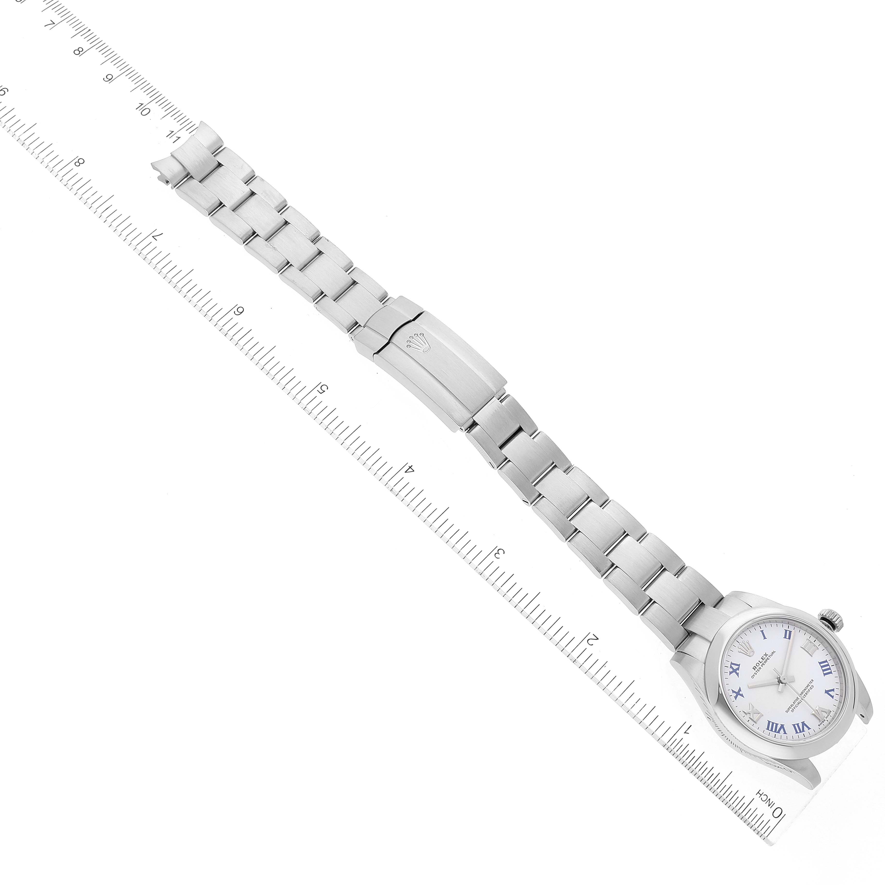 The image shows a laid-flat Rolex Mid-Size 177200 Women
s Stainless Steel White Dial 177200 Women
s Stainless Steel White Dial watch with a metal band and clasp, positioned next to a measuring ruler.