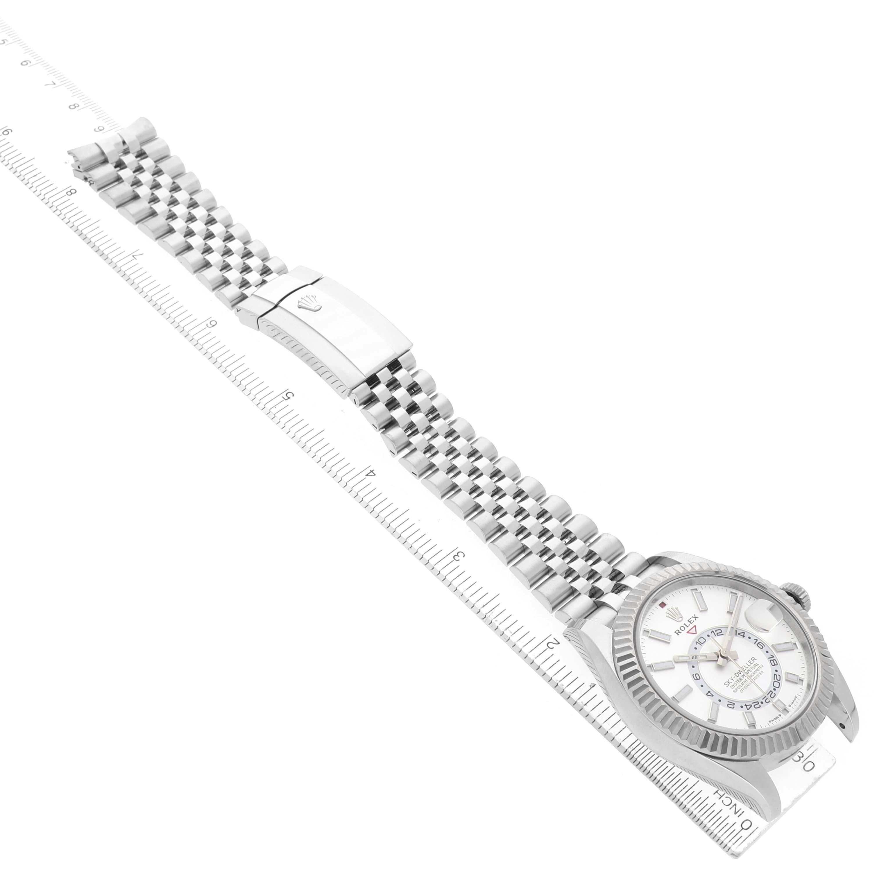 The Rolex Sky-Dweller 336934 Men's Stainless Steel White Dial watch is shown at an angle displaying its face, bezel, bracelet, and clasp, alongside a ruler.