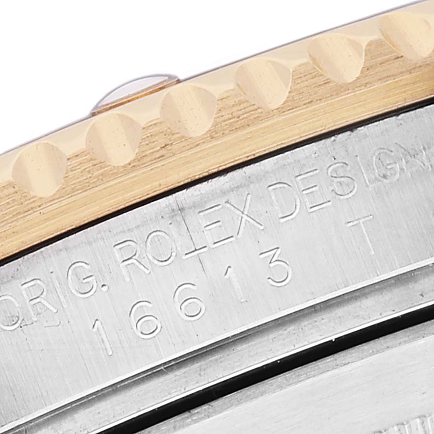 The image shows a close-up of the engraved side of a Rolex Submariner 16613 Men
s Steel and Gold (two tone) Blue Dial 16613 Men
s Steel and Gold (two tone) Blue Dial watch case and bezel.