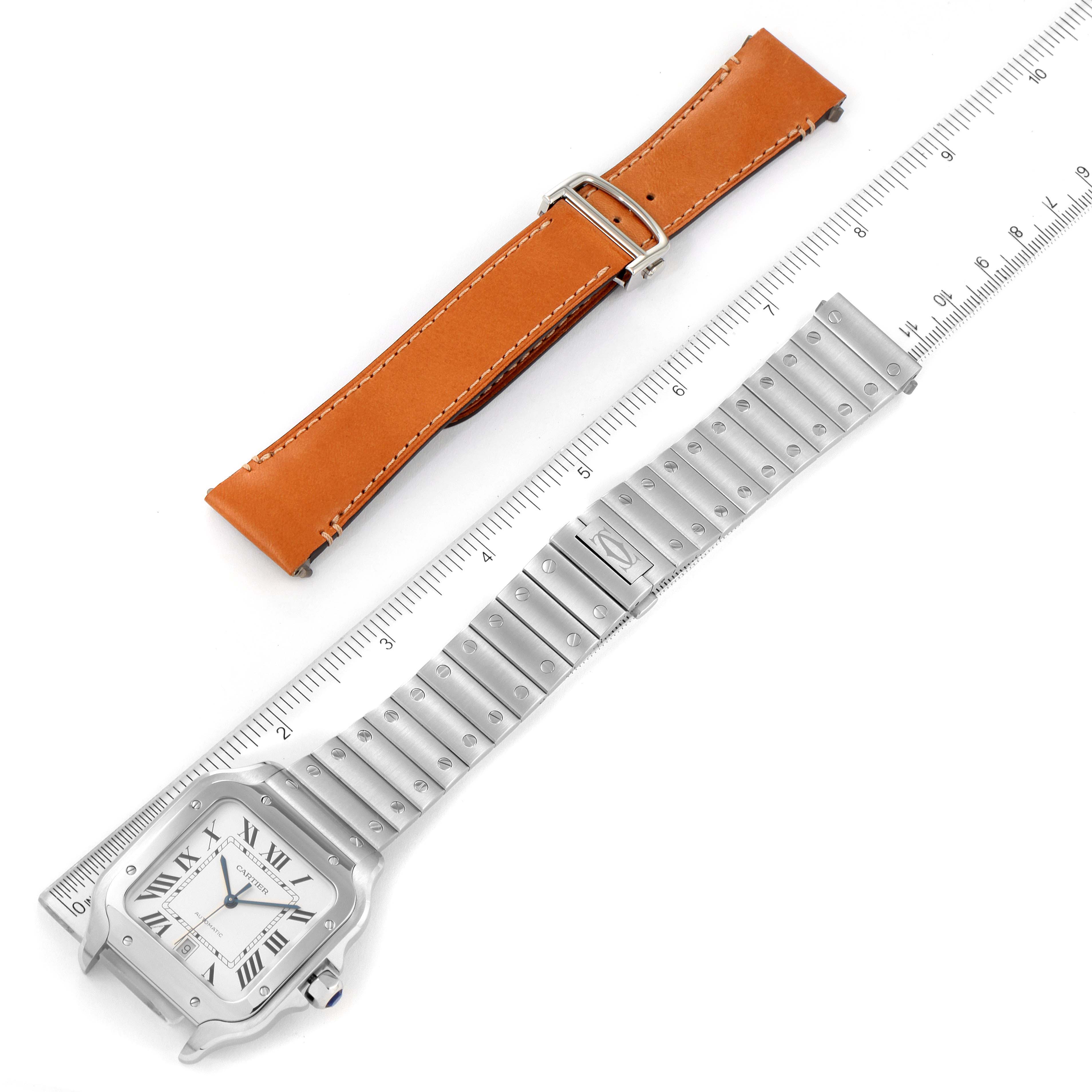 This image shows a Santos model Cartier watch with a metal bracelet and an additional brown leather strap, placed alongside a ruler.