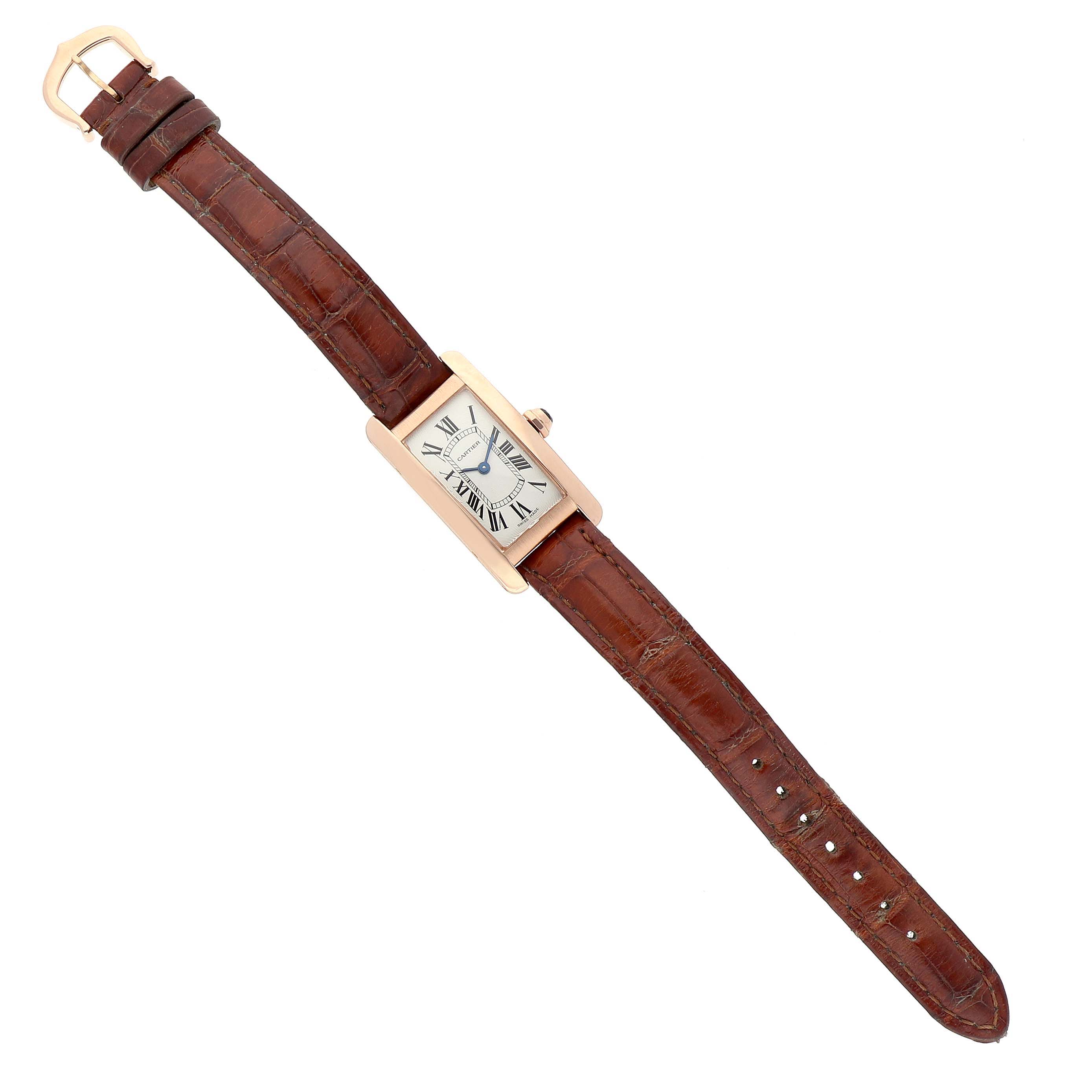 The Cartier Tank Américaine watch is shown from above, displaying its face, brown leather strap, and buckle.