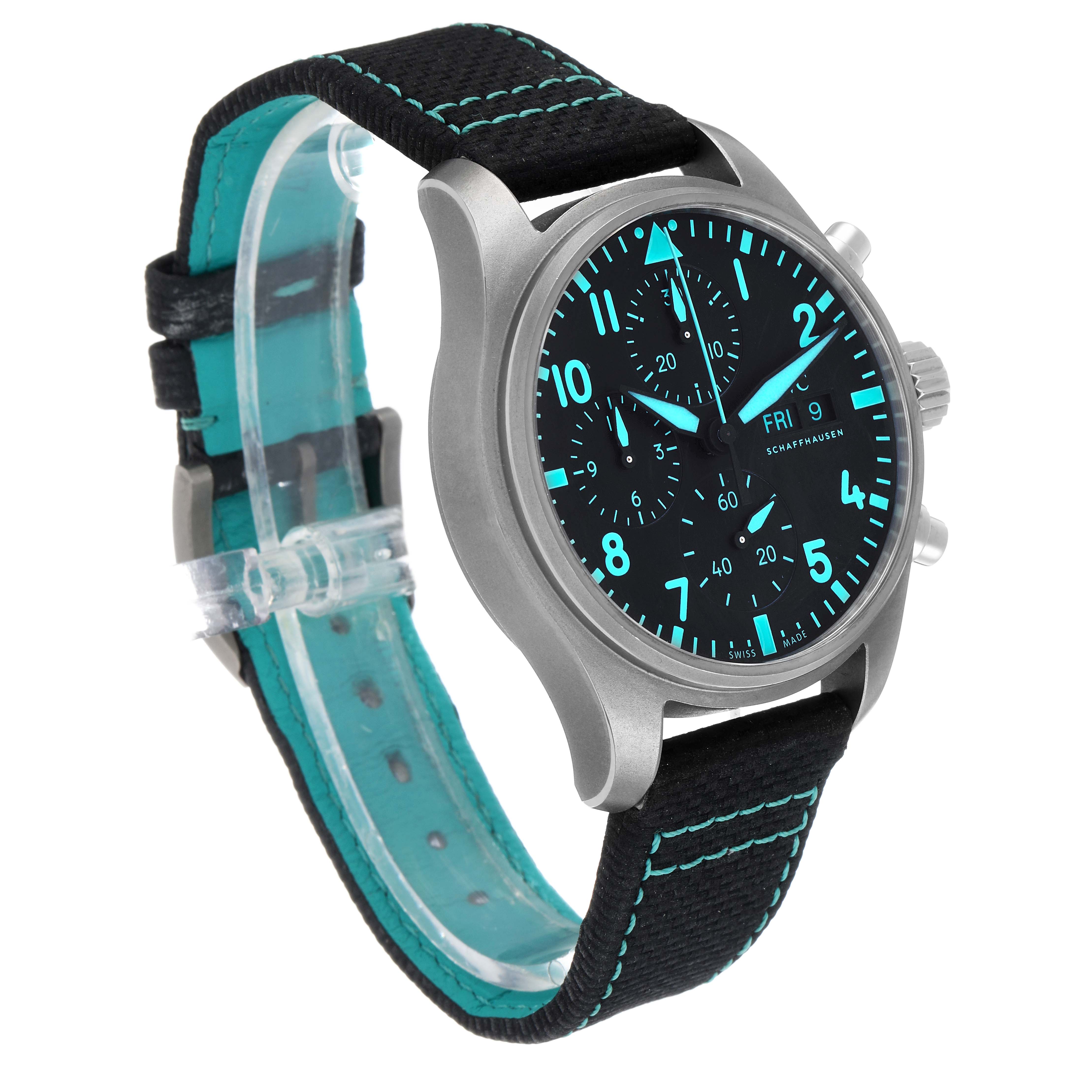 The IWC Pilot IW388114 Men's Titanium Black Dial watch is shown at a three-quarter angle, highlighting the dial, case, buttons, and strap with teal stitching.