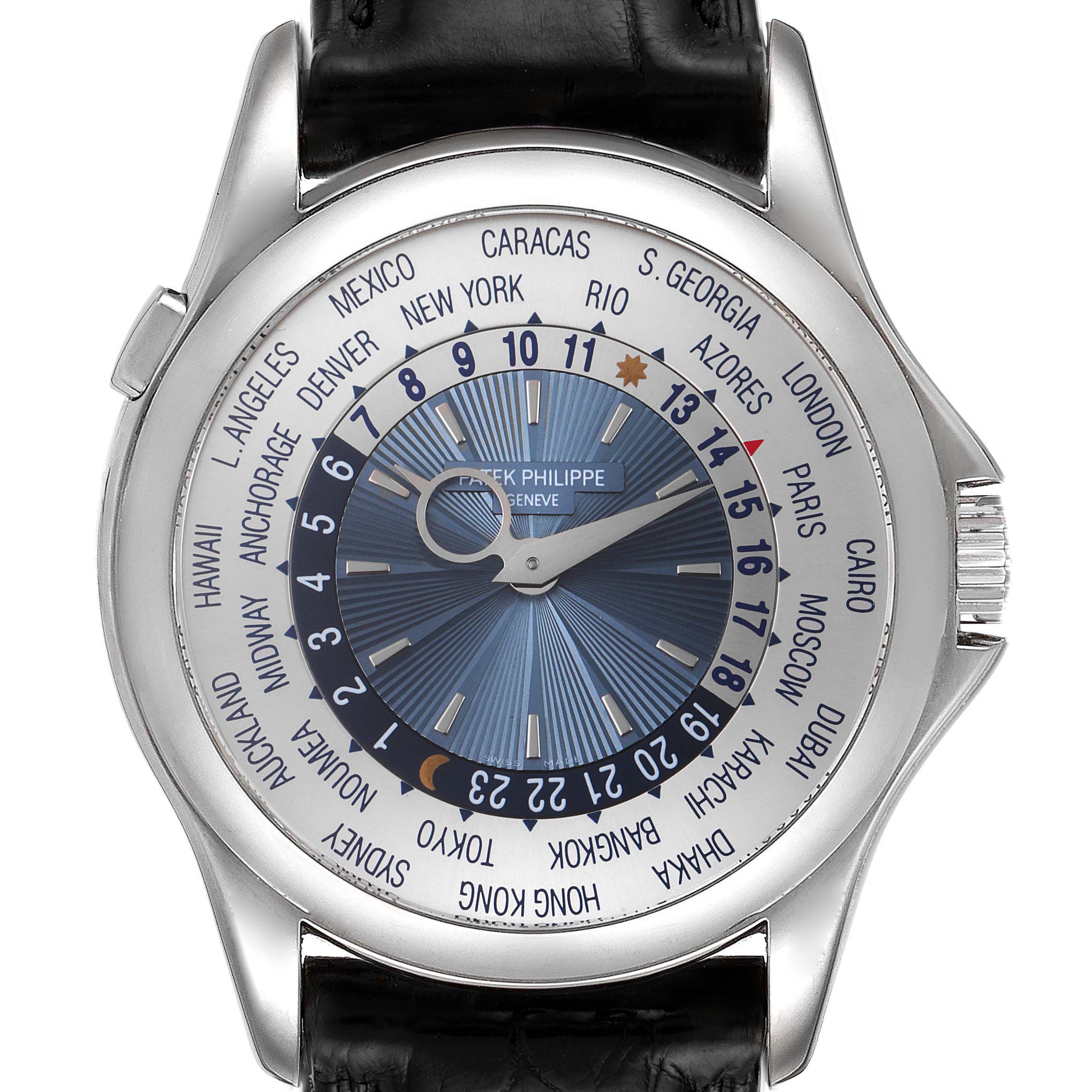 The image displays a frontal view of a Patek Philippe Complications 5130P Men's Platinum Silver Dial 5130P Men's Platinum Silver Dial watch, featuring a blue dial with a world time display and a black leather strap.