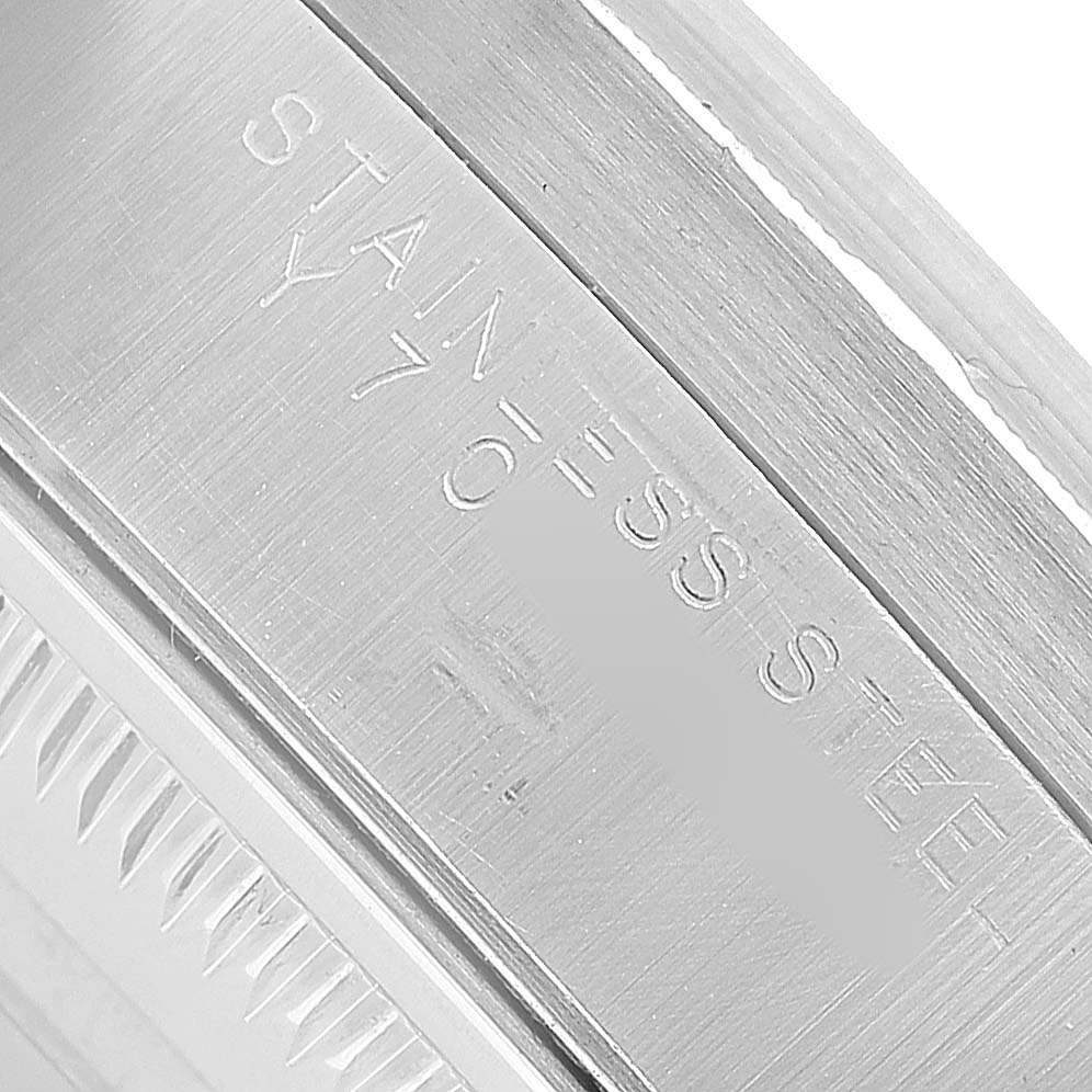 The image shows a close-up of the stainless steel case on a Rolex Date 15210 Men's Stainless Steel Silver Dial model, highlighting the material engraving.