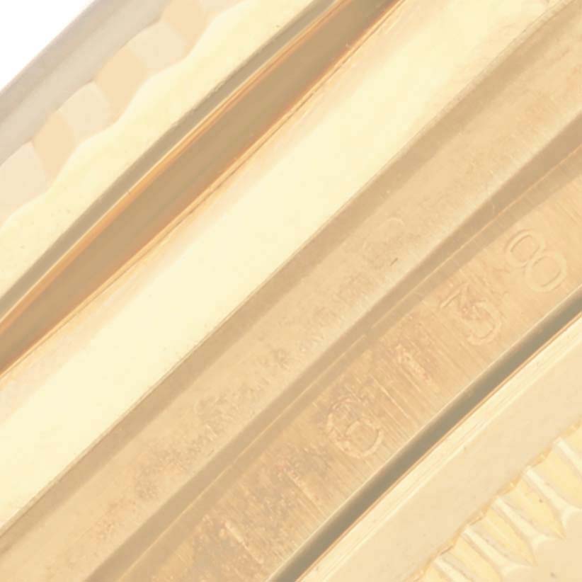 The image shows a close-up of the side of a gold bezel, likely from a Rolex Datejust 116138 Men's Yellow Gold White Dial 116138 Men's Yellow Gold White Dial.