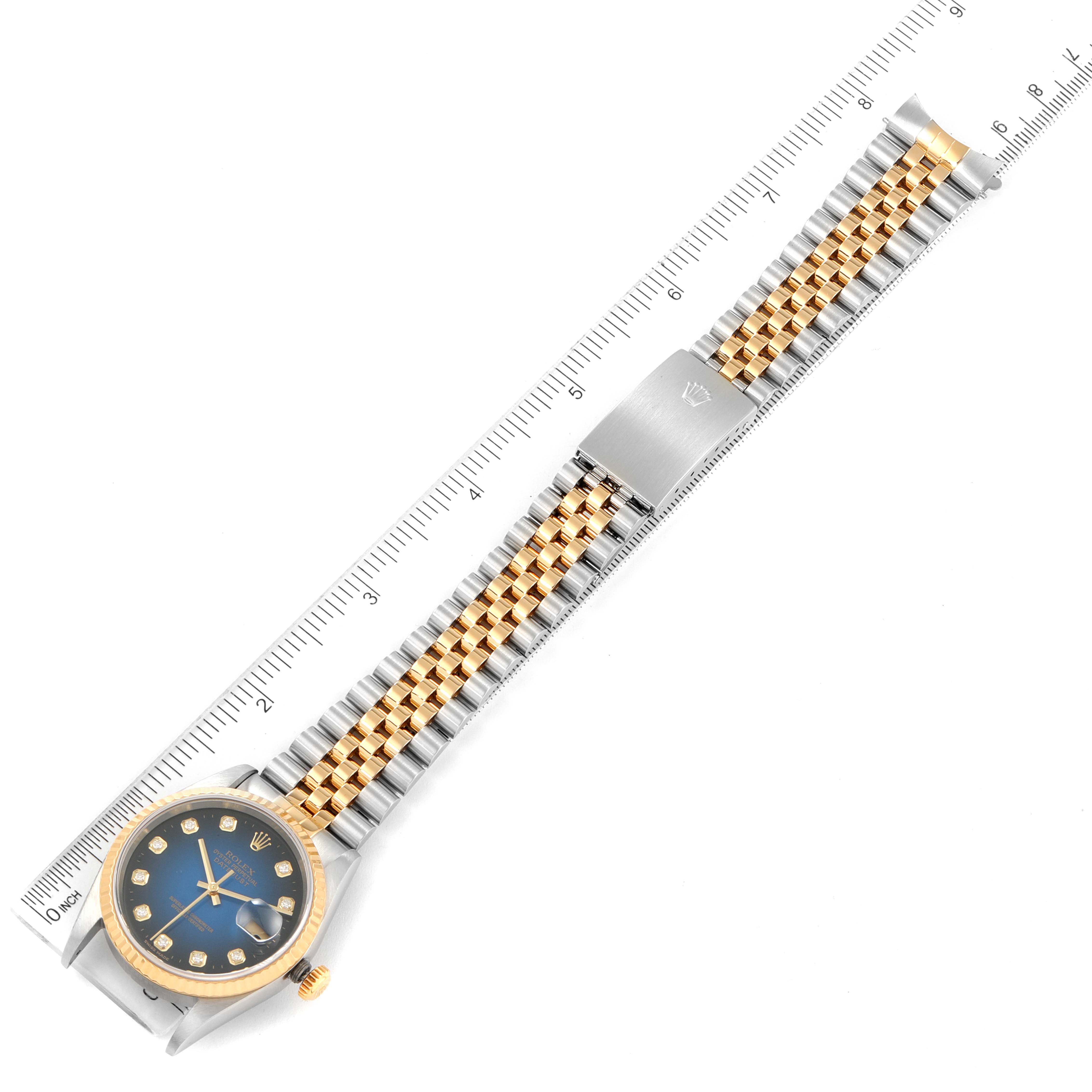 This image shows a Rolex Datejust 16233 Men's Steel and Gold (two tone) Blue Dial 16233 Men's Steel and Gold (two tone) Blue Dial watch laid flat with the dial, bezel, crown, and bracelet fully visible alongside a ruler.