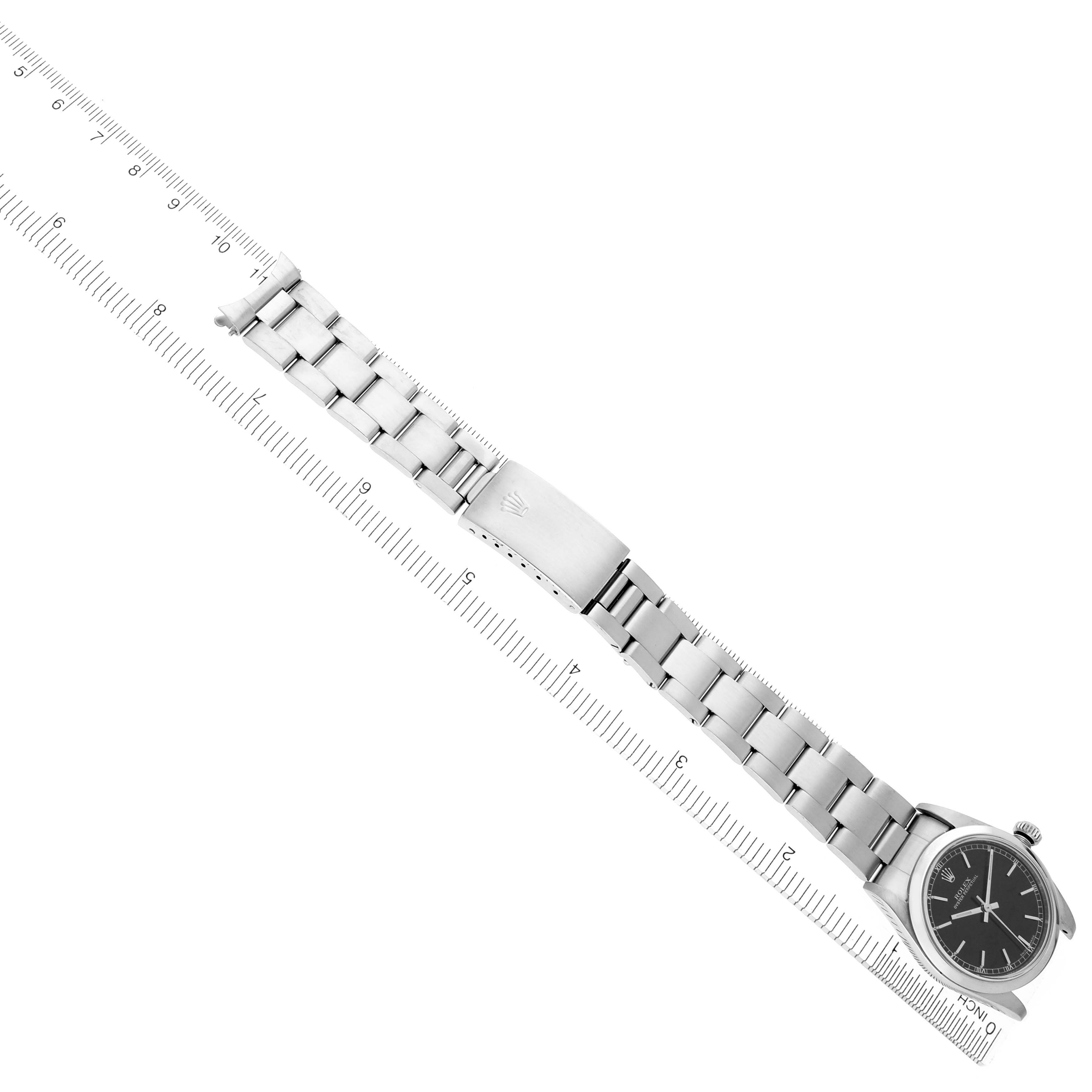 The image shows a Rolex Mid-Size 77080 Women's Stainless Steel Black Dial 77080 Women's Stainless Steel Black Dial watch lying flat, displaying the bracelet, clasp, and face from a top-down angle alongside a ruler.