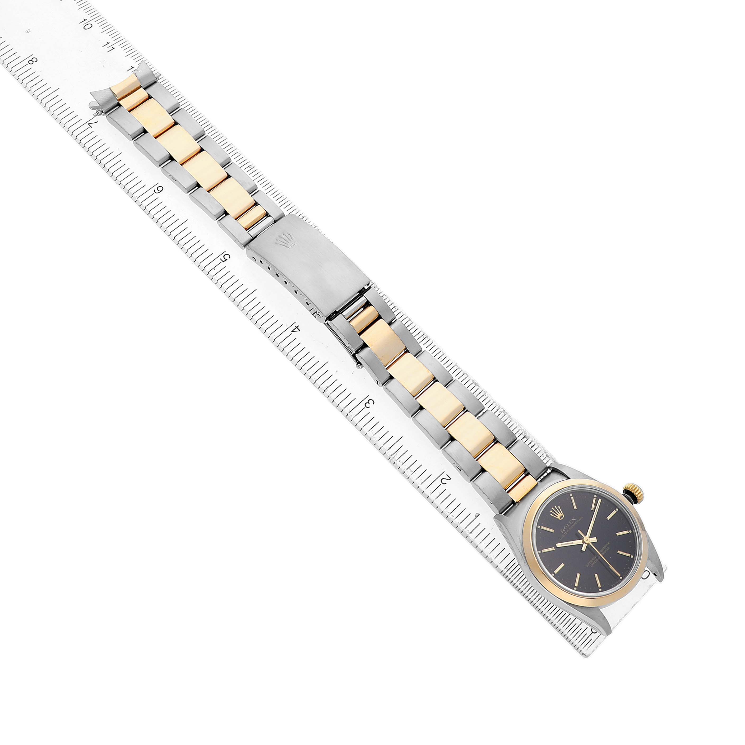 The Rolex Oyster Perpetual 67483 Women's Steel and Gold (two tone) Black Dial watch is shown angled slightly from above, displaying its band, clasp, and face.