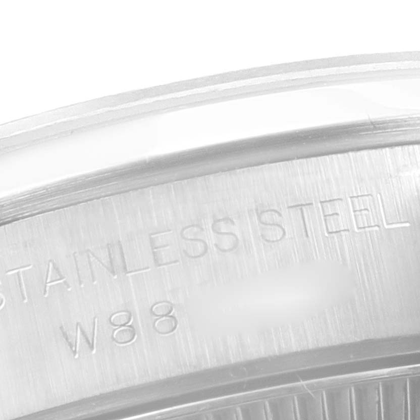 This close-up image of a Rolex Oyster Perpetual 67180 Women
s Stainless Steel White Dial 67180 Women
s Stainless Steel White Dial watch shows a section of the stainless steel case with engraved text.
