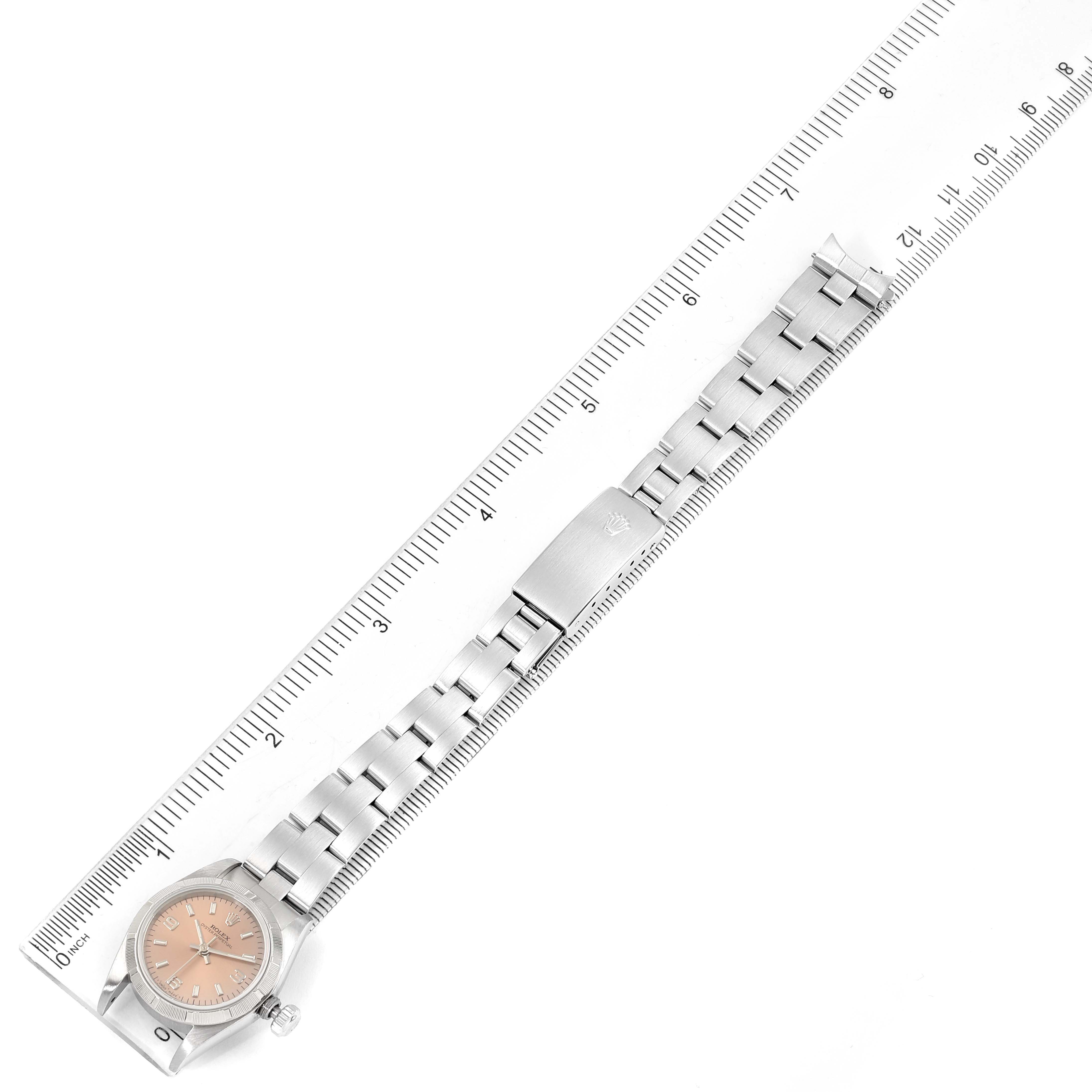 This image shows a Rolex Oyster Perpetual 67230 Women's Stainless Steel Pink Dial 67230 Women's Stainless Steel Pink Dial watch lying flat, with a ruler measuring its length.