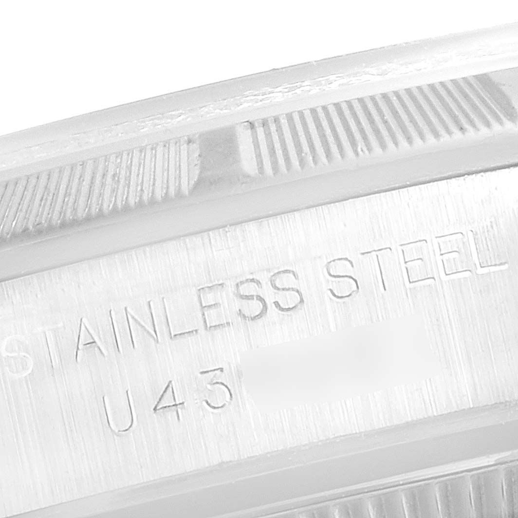 This image shows a close-up of the engraved side of the stainless steel case of a Rolex Oyster Perpetual 67230 Women's Stainless Steel Pink Dial 67230 Women's Stainless Steel Pink Dial watch.