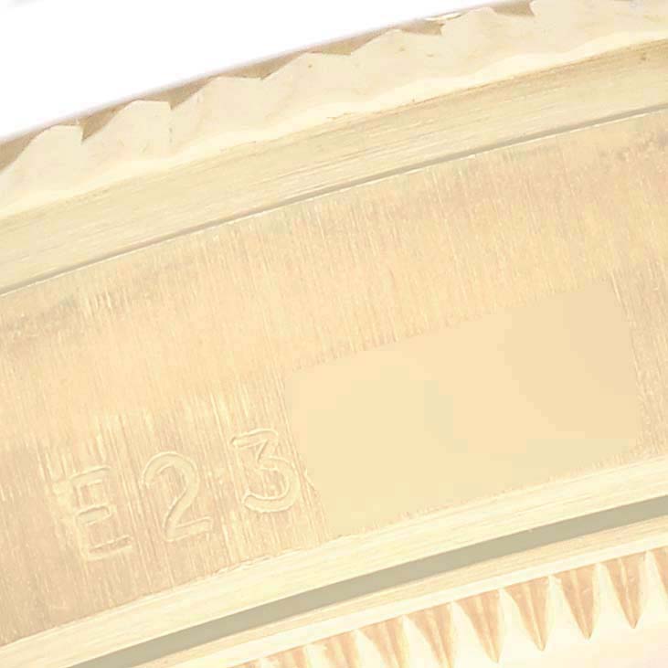 The image shows a close-up of the edge of a Rolex Mid-Size model, highlighting the engraved detail.