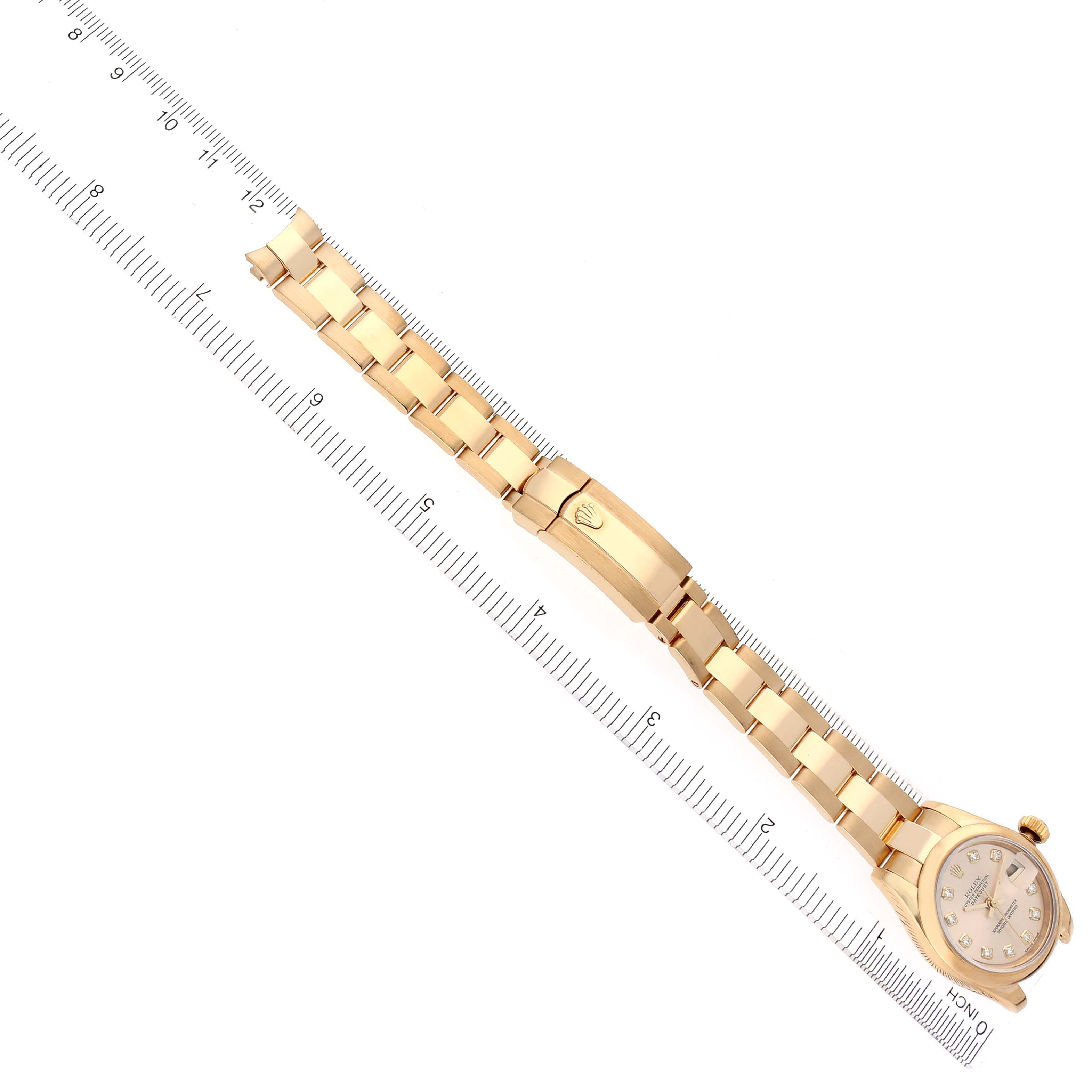 The Rolex President 179168 Women's Yellow Gold Champagne Dial 179168 Women's Yellow Gold Champagne Dial watch is shown laid flat with its bracelet fully extended alongside a ruler for scale.