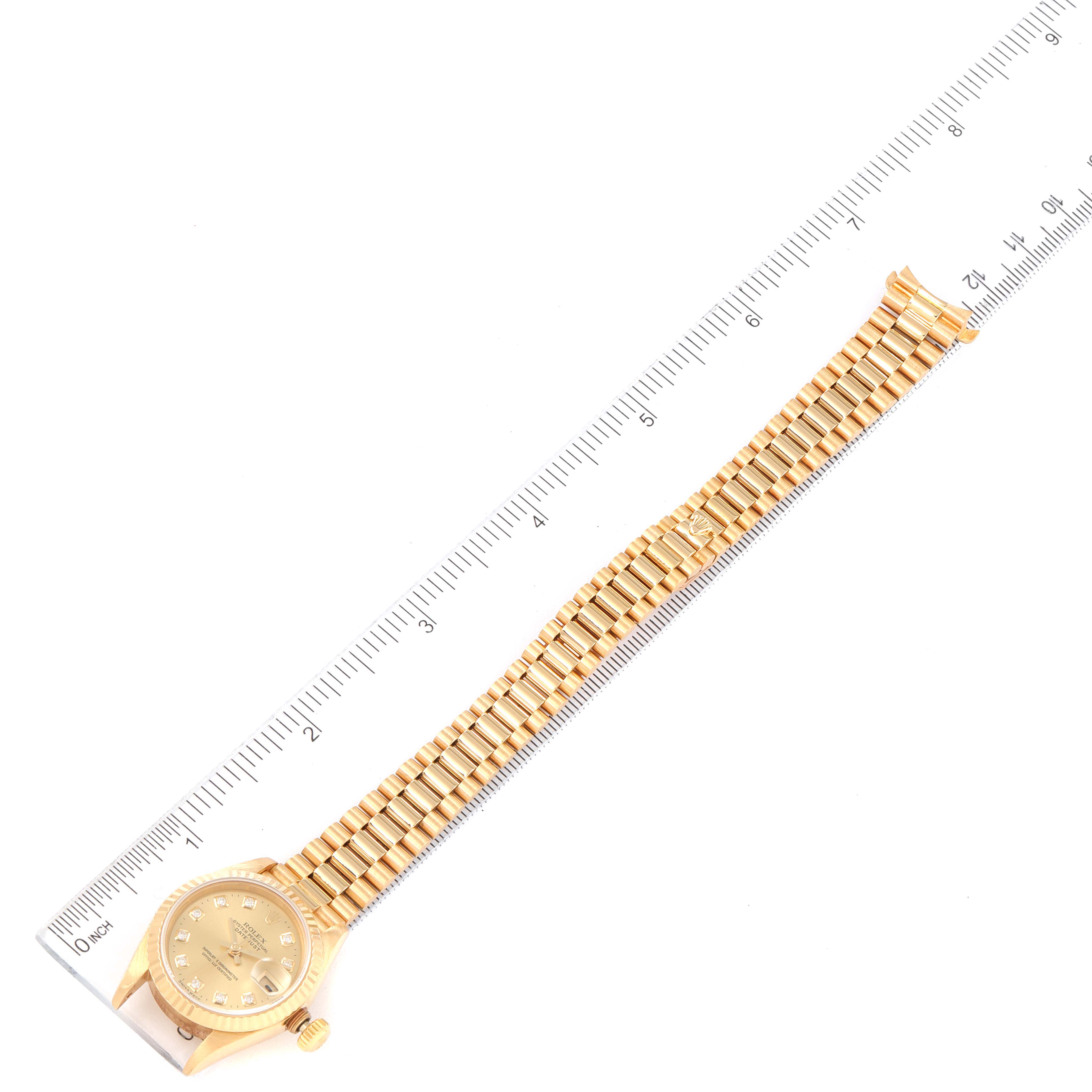 The Rolex President 69178 Women
s Yellow Gold Champagne Dial 69178 Women
s Yellow Gold Champagne Dial model watch is shown from a top-down angle with its band parallel to a ruler.