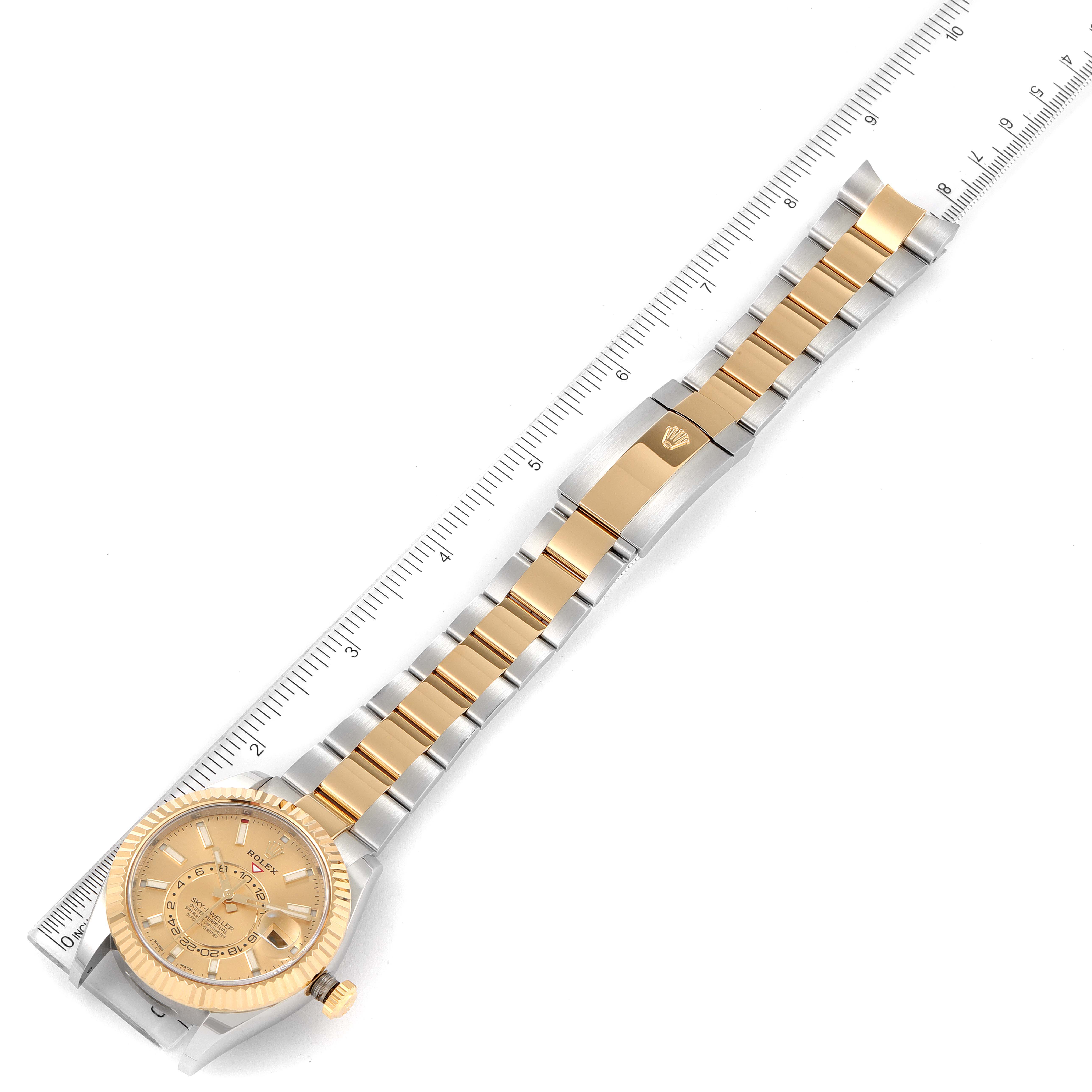 This image shows the Rolex Sky-Dweller 326933 Men's Steel and Gold (two tone) Champagne Dial 326933 Men's Steel and Gold (two tone) Champagne Dial watch laid out flat with the full bracelet and face exposed next to a ruler for scale.