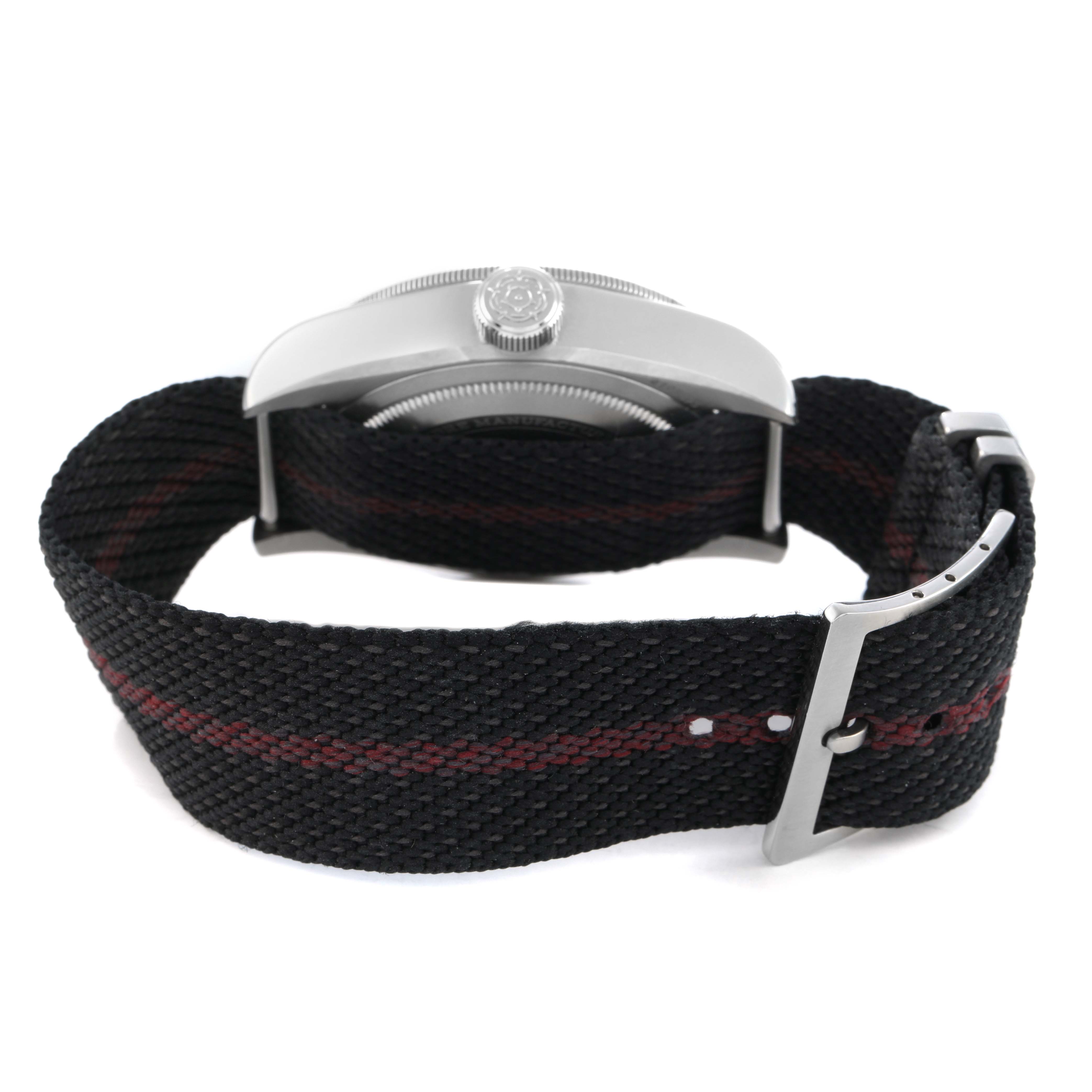 The Tudor Heritage Black Bay 79830RB Men's Stainless Steel Black Dial watch is shown from the side, displaying the crown and fabric strap with a clasp.