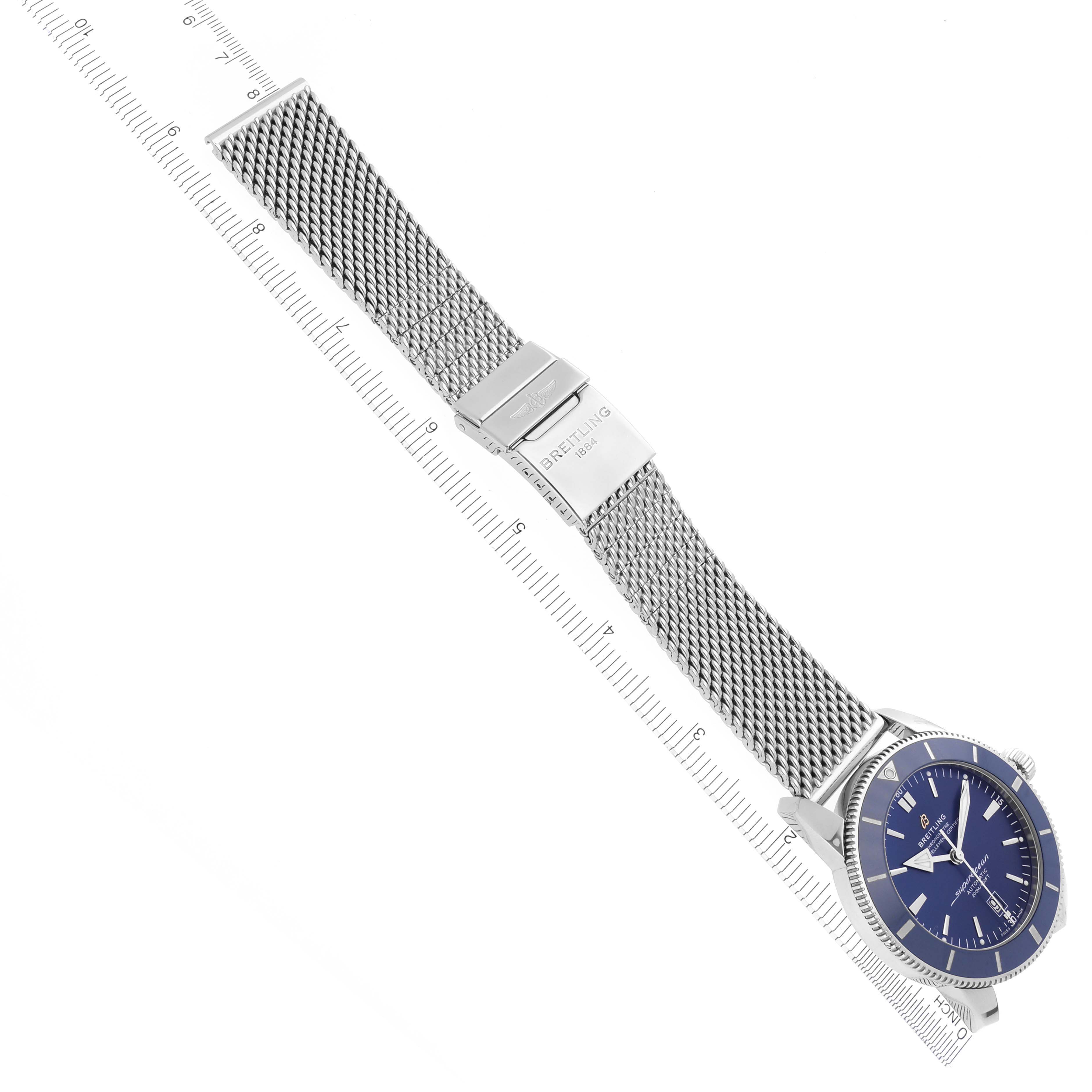 The Breitling Superocean AB2020161C1A1 Men's Stainless Steel Blue Dial AB2020161C1A1 Men's Stainless Steel Blue Dial watch is shown at a diagonal angle, displaying its blue dial and metal mesh strap next to a ruler.