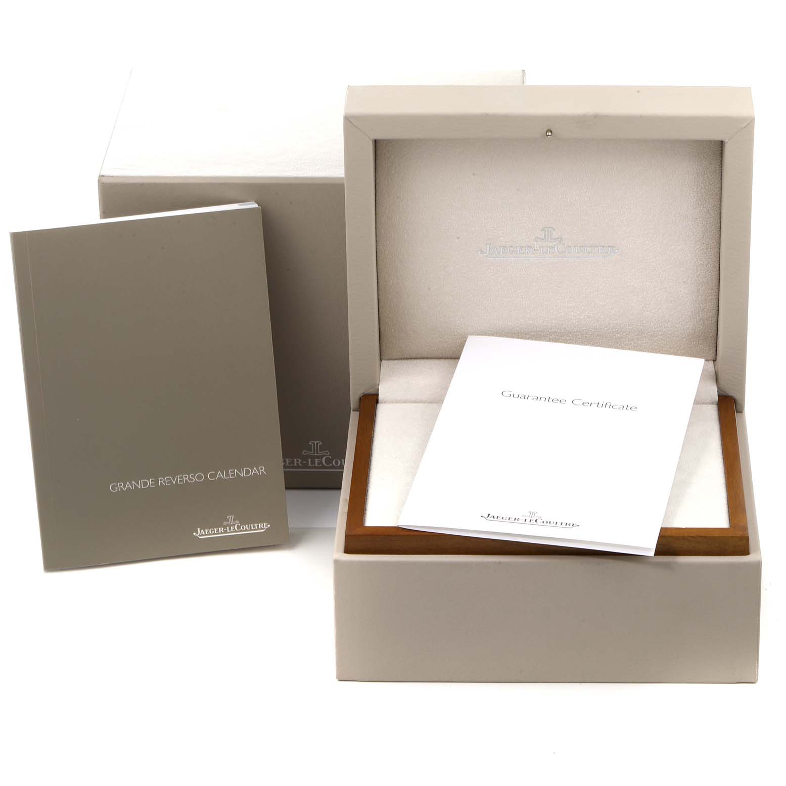 The image shows an open Jaeger-LeCoultre Reverso watch box, a guarantee certificate, and a Grande Reverso Calendar booklet.