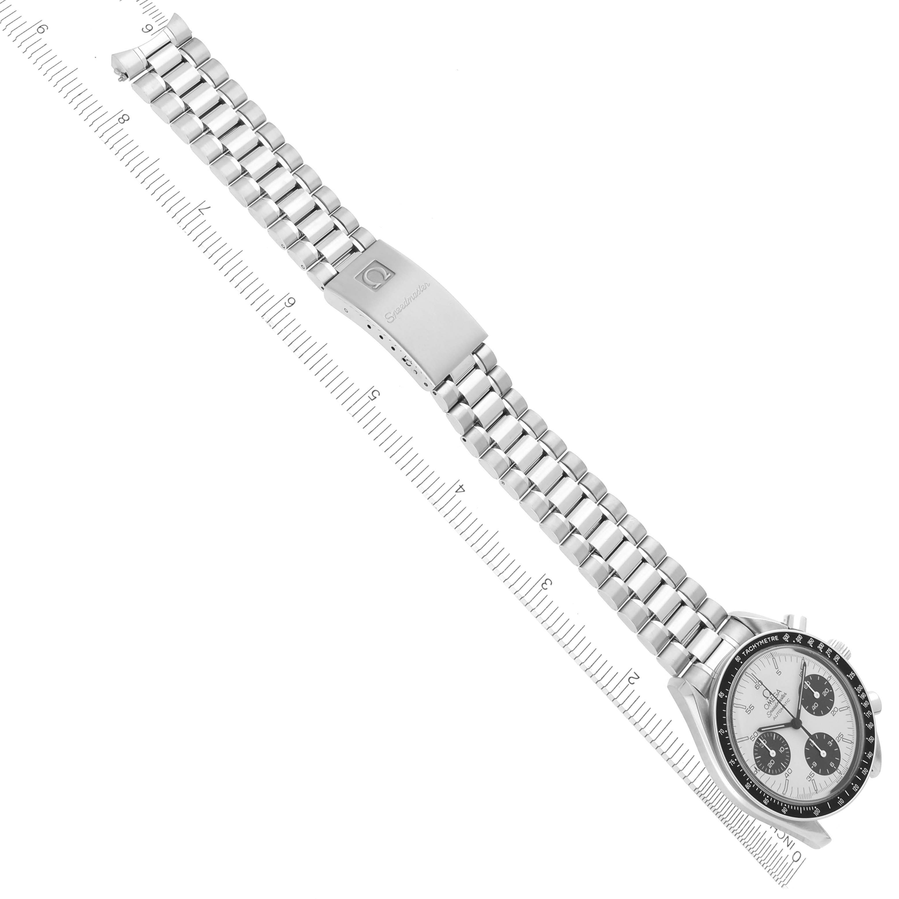 The Omega Speedmaster 3510.21.00 Men
s Stainless Steel White Dial 3510.21.00 Men
s Stainless Steel White Dial watch is shown at an angle with a view of the face, bezel, and full metal bracelet alongside a ruler.