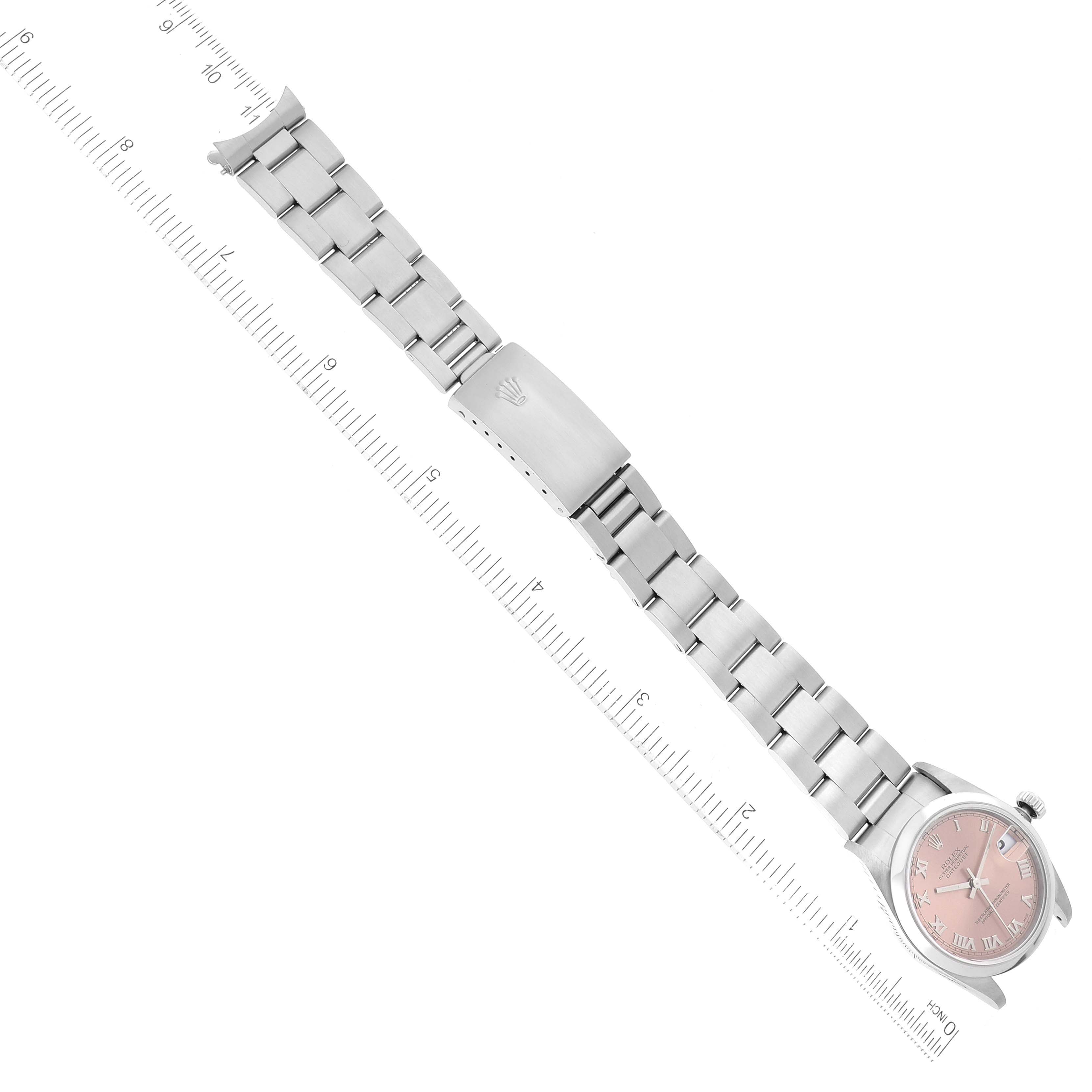 The Rolex Mid-Size 78240 Women's Stainless Steel Pink Dial 78240 Women's Stainless Steel Pink Dial model watch is shown at an overhead angle, featuring its face, bracelet, and deployment clasp next to a ruler.