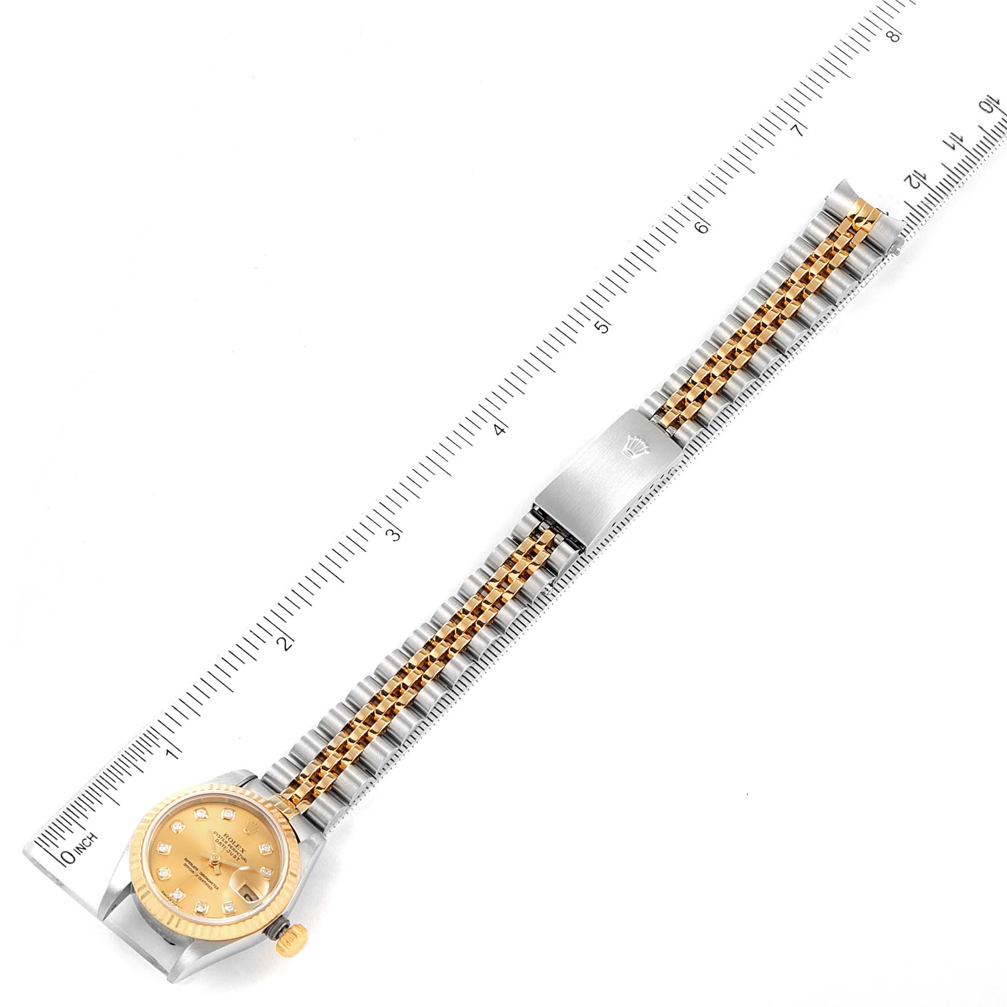 The image shows a top view of a Rolex Datejust 79173 Women
s Steel and Gold (two tone) Champagne Dial 79173 Women
s Steel and Gold (two tone) Champagne Dial watch with a ruler for measuring the band length.