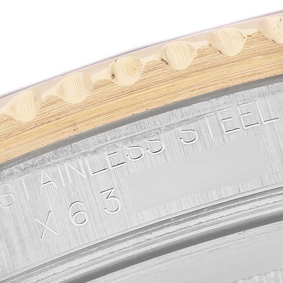 The image shows a close-up of the engraved case side of a Rolex GMT-Master 16713 Men's Steel and Gold (two tone) Brown Dial, highlighting the "STAINLESS STEEL" text.
