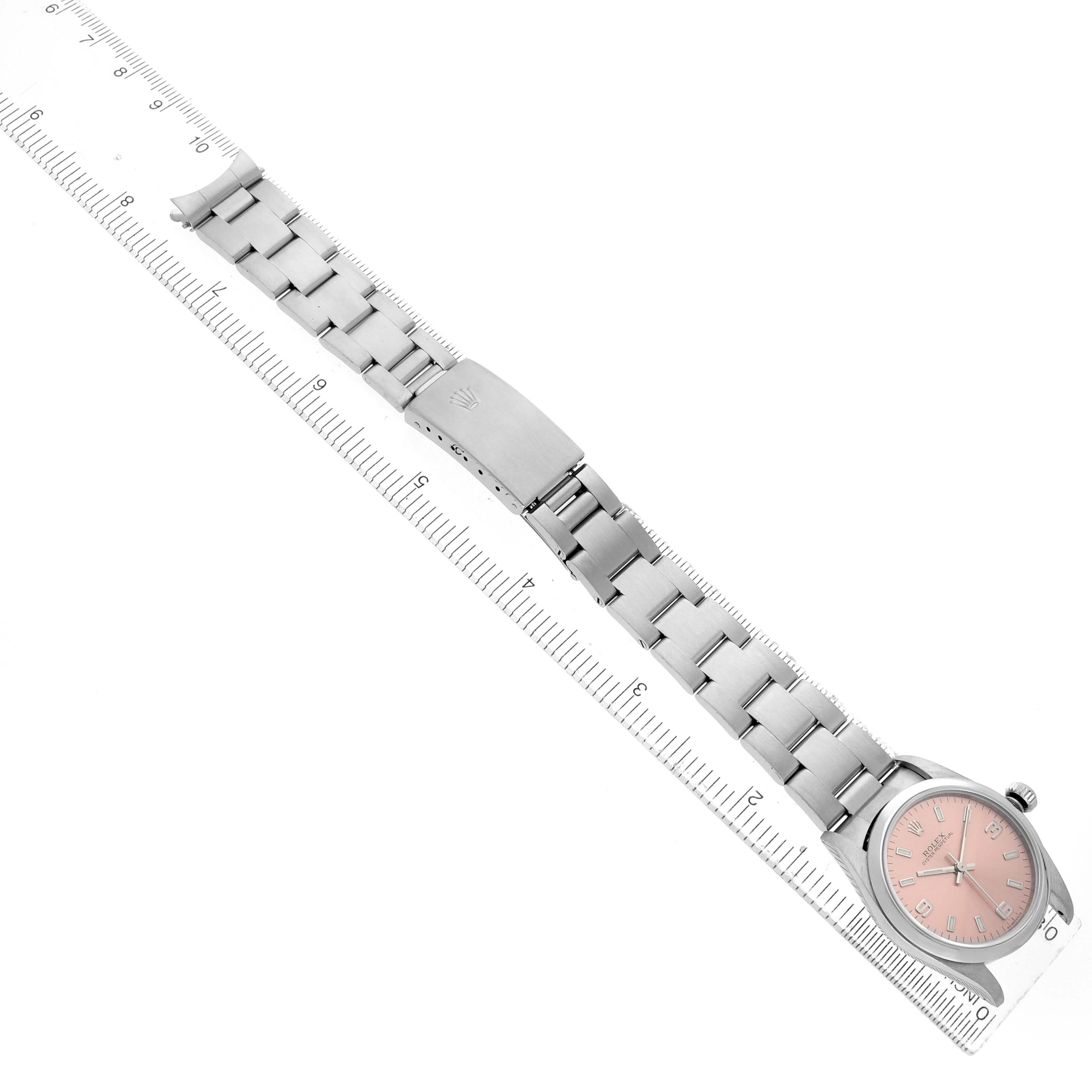 The image shows a Rolex Oyster Perpetual 77080 Women's Stainless Steel Pink Dial watch laid flat next to a ruler, displaying the entire bracelet and face.