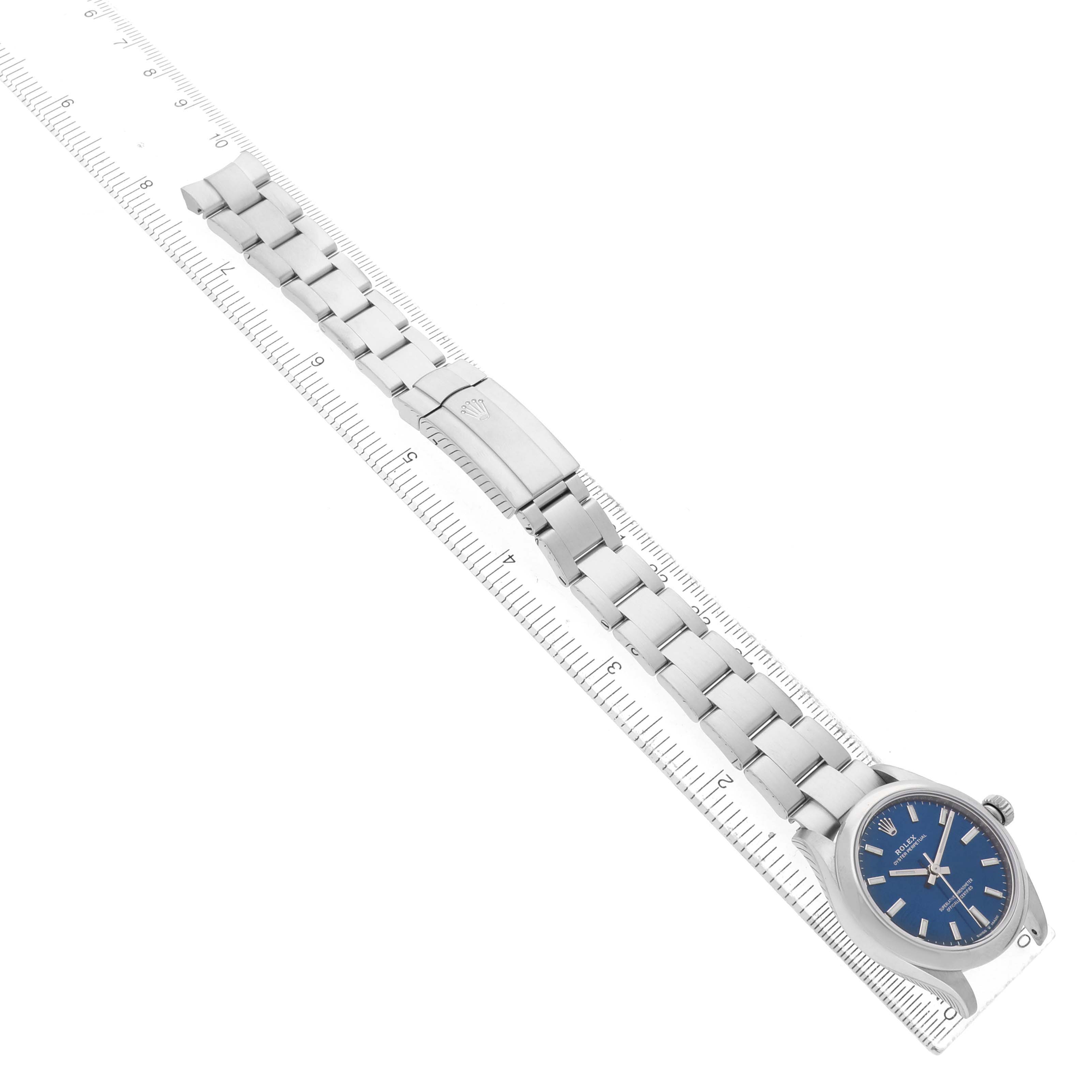The Rolex Oyster Perpetual 277200 Women's Stainless Steel Blue Dial watch is shown from a top-down angle, showcasing the face, bracelet, and clasp.