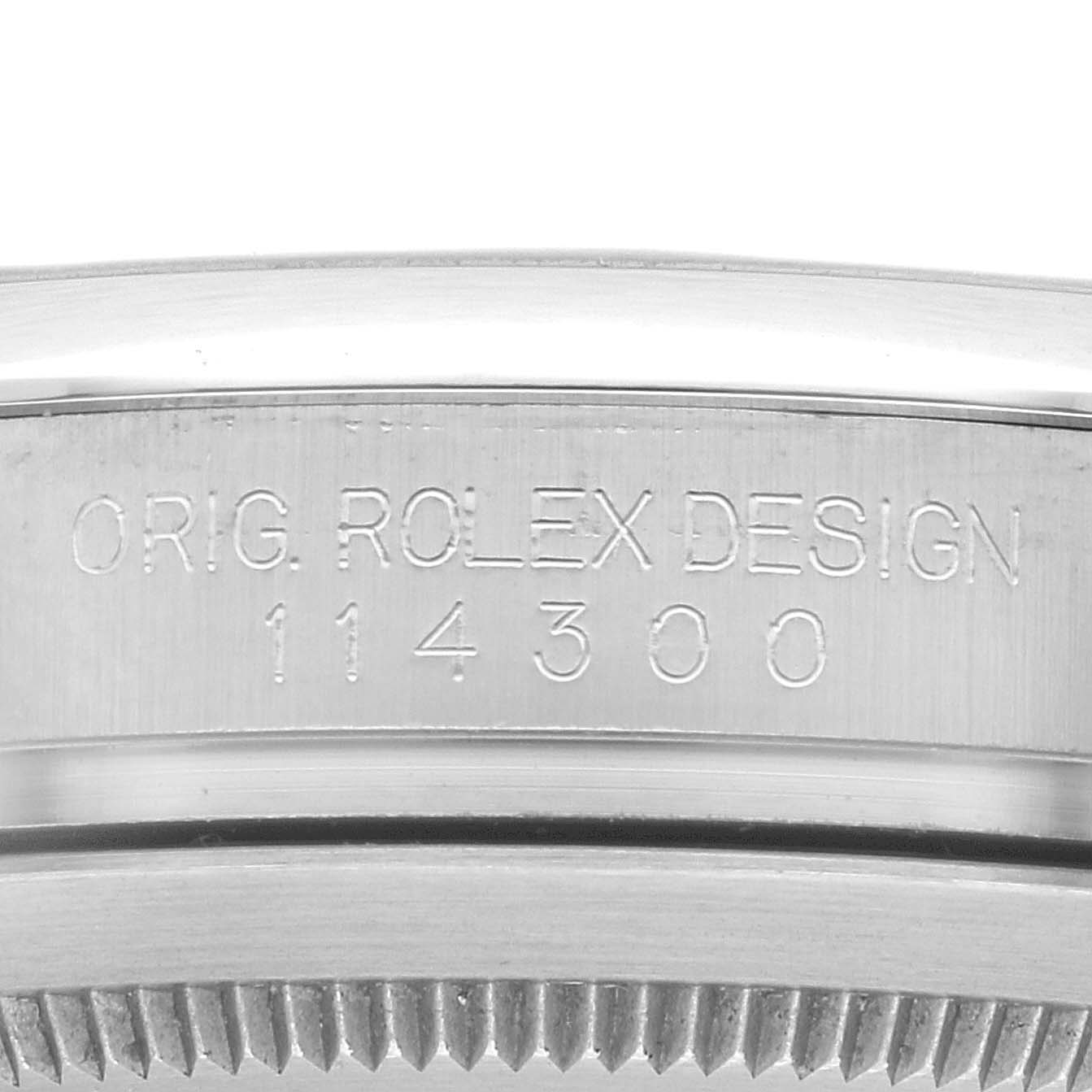 The image shows a close-up of the model number and design engraving on the side of the Rolex Oyster Perpetual 114300 Men
s Stainless Steel Purple Dial 114300 Men
s Stainless Steel Purple Dial watch case.