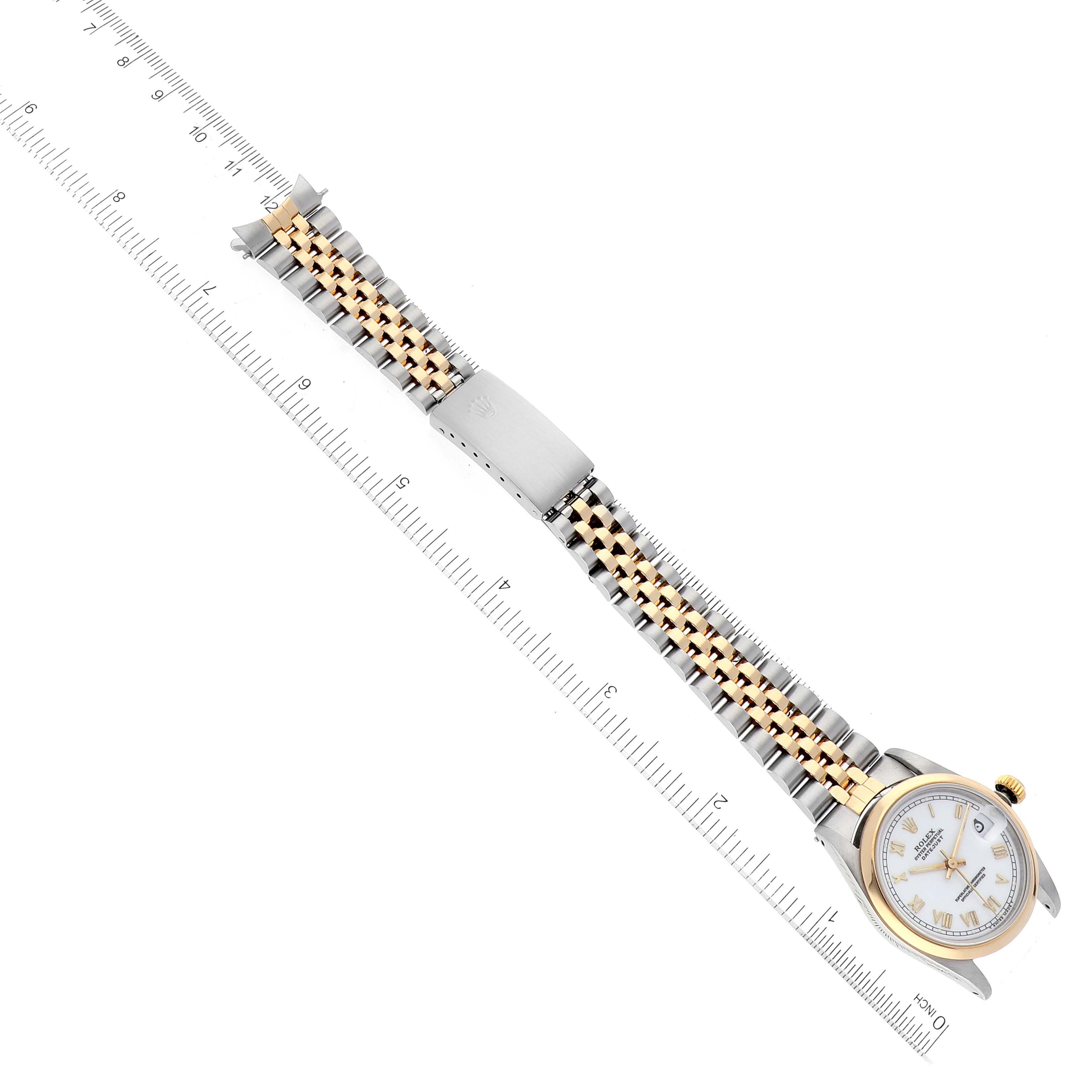 The image shows a top view of a Rolex Mid-Size 68243 Women's Steel and Gold (two tone) White Dial 68243 Women's Steel and Gold (two tone) White Dial model watch, displaying its dial, case, and bracelet next to a ruler for scale.