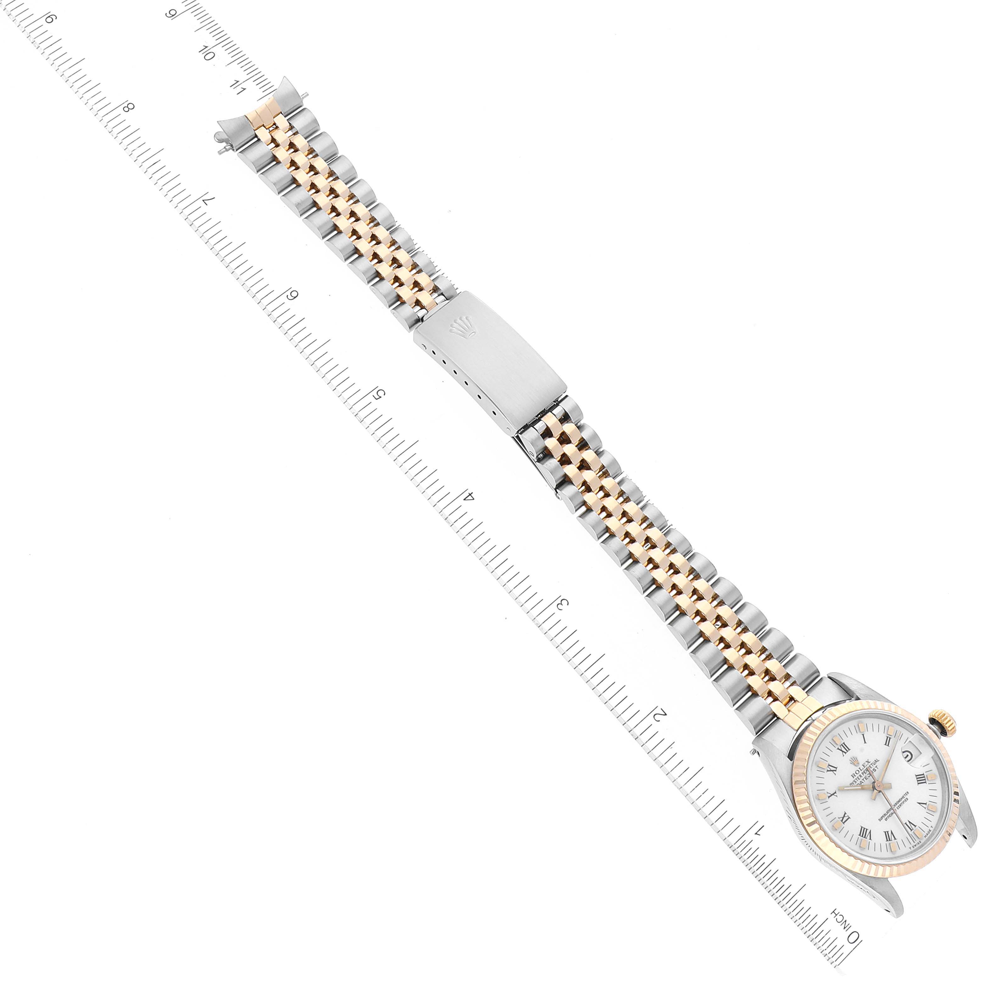 The image shows a Rolex Mid-Size 68273 Women
s Steel and Gold (two tone) White Dial 68273 Women
s Steel and Gold (two tone) White Dial model watch in a top-down view, featuring the full face and band along with a measuring ruler.