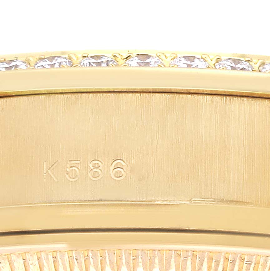 The image shows a close-up of the gold bezel of a Rolex President 179138 Women's Yellow Gold Champagne Dial 179138 Women's Yellow Gold Champagne Dial watch, partially featuring diamonds and an engraved serial number.