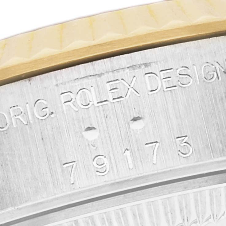 This close-up image shows part of the case and bezel of a Rolex Datejust 79173 Women's Steel and Gold (two tone) Blue Dial 79173 Women's Steel and Gold (two tone) Blue Dial, displaying some of its engraved markings.