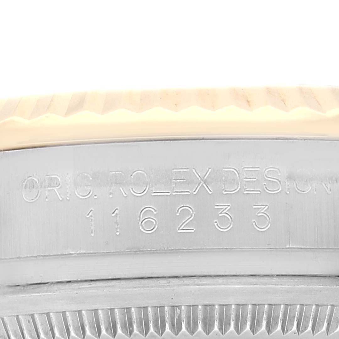 This image shows a close-up of the side of a Rolex Datejust 116233 Men's Steel and Gold (two tone) Silver Dial 116233 Men's Steel and Gold (two tone) Silver Dial watch, displaying its engraved serial number and part of its bezel.