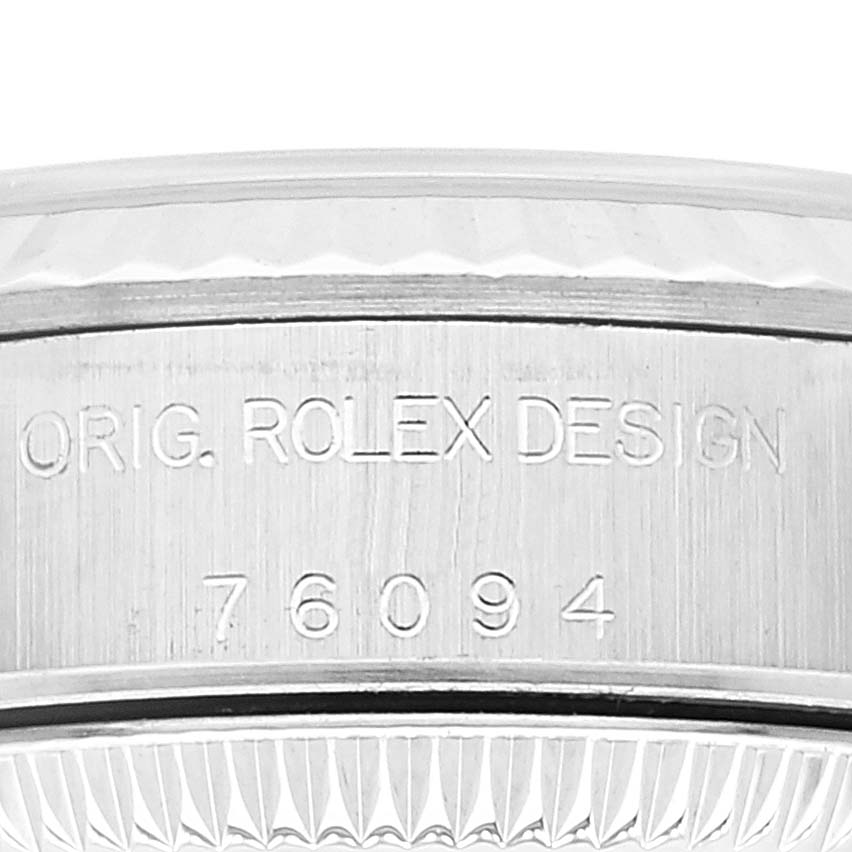 The image shows a close-up of the side of a Rolex Oyster Perpetual 76094 Women
s Stainless Steel Silver Dial 76094 Women
s Stainless Steel Silver Dial watch with the engraving "ORIG. ROLEX DESIGN 76094."
