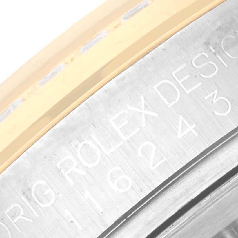 This close-up image features the side of a Rolex Datejust 116243 Men's Steel and Gold (two tone) Champagne Dial 116243 Men's Steel and Gold (two tone) Champagne Dial watch with engraved text "ORIG ROLEX DESIGN."