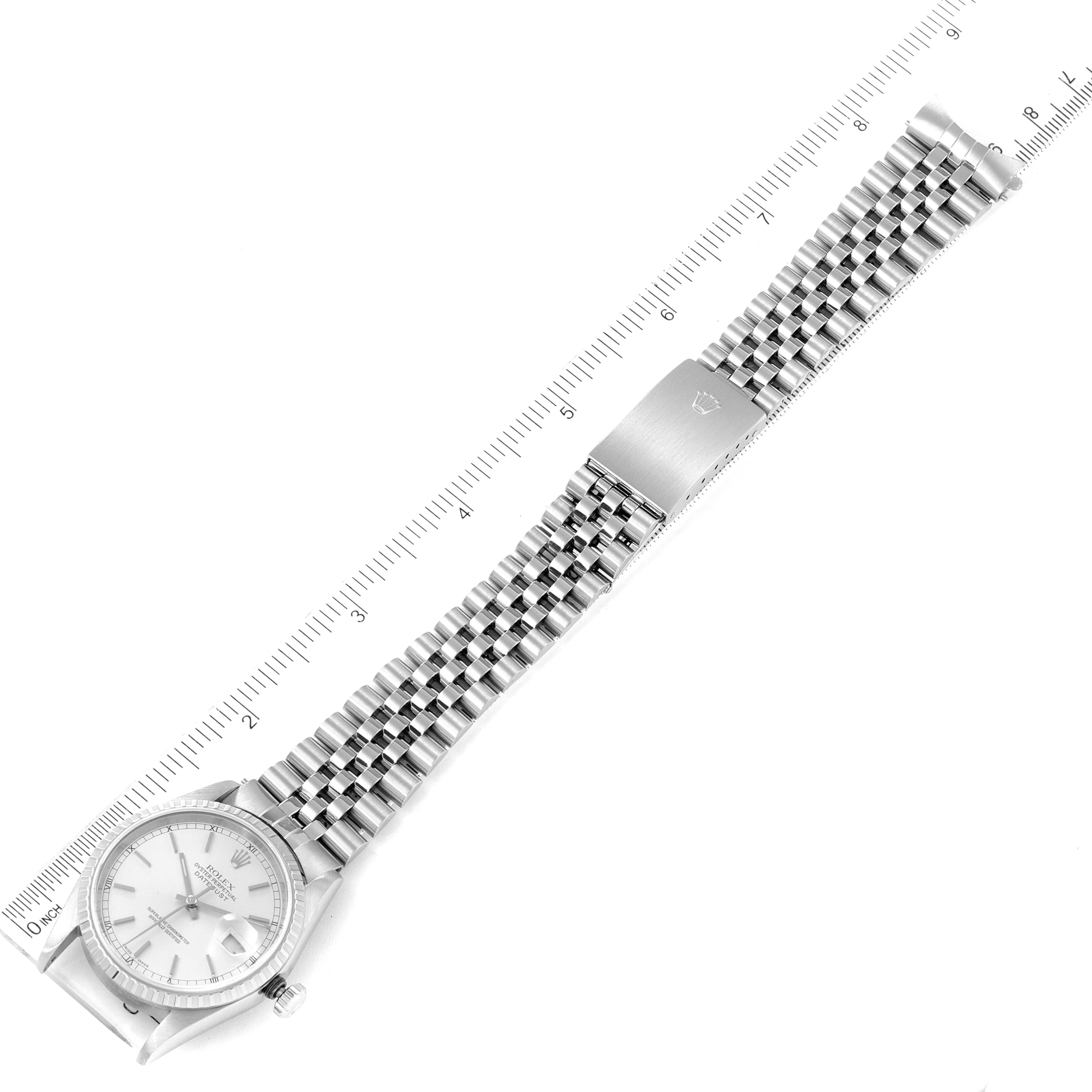 The image shows a top view of a Rolex Datejust 16220 Men's Stainless Steel Silver Dial 16220 Men's Stainless Steel Silver Dial watch laid flat alongside a ruler, displaying the dial and Jubillee bracelet.