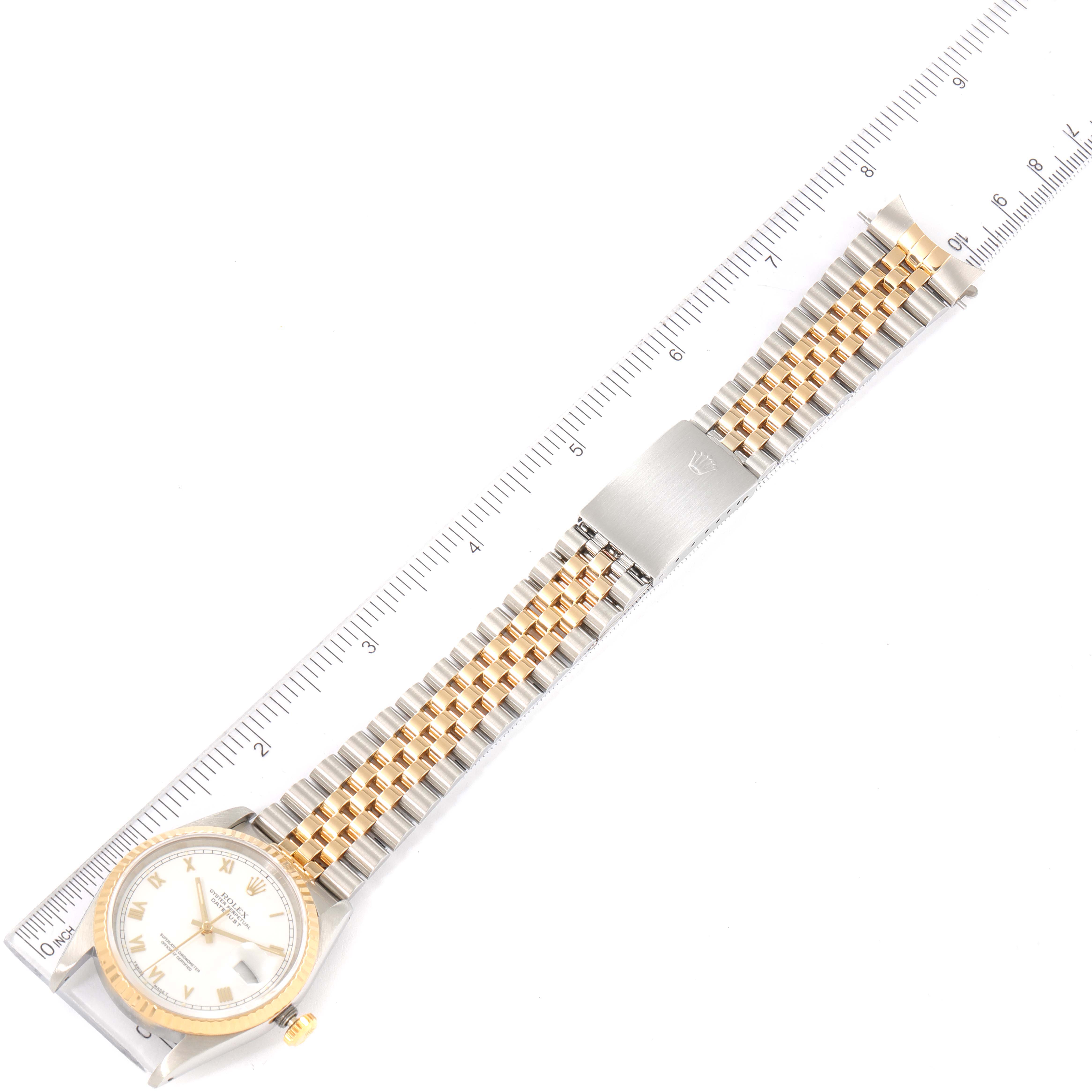 The Rolex Datejust 16233 Men's Steel and Gold (two tone) White Dial 16233 Men's Steel and Gold (two tone) White Dial watch is shown laid flat, facing up, with the entire bracelet and clasp visible, next to a measuring ruler.