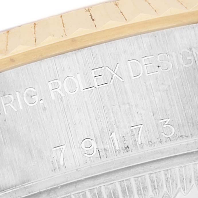 This is a close-up of the Rolex Datejust 79173 Women's Steel and Gold (two tone) Mother of Pearl Dial 79173 Women's Steel and Gold (two tone) Mother of Pearl Dial model, showing the engraved serial numbers and part of the fluted bezel.