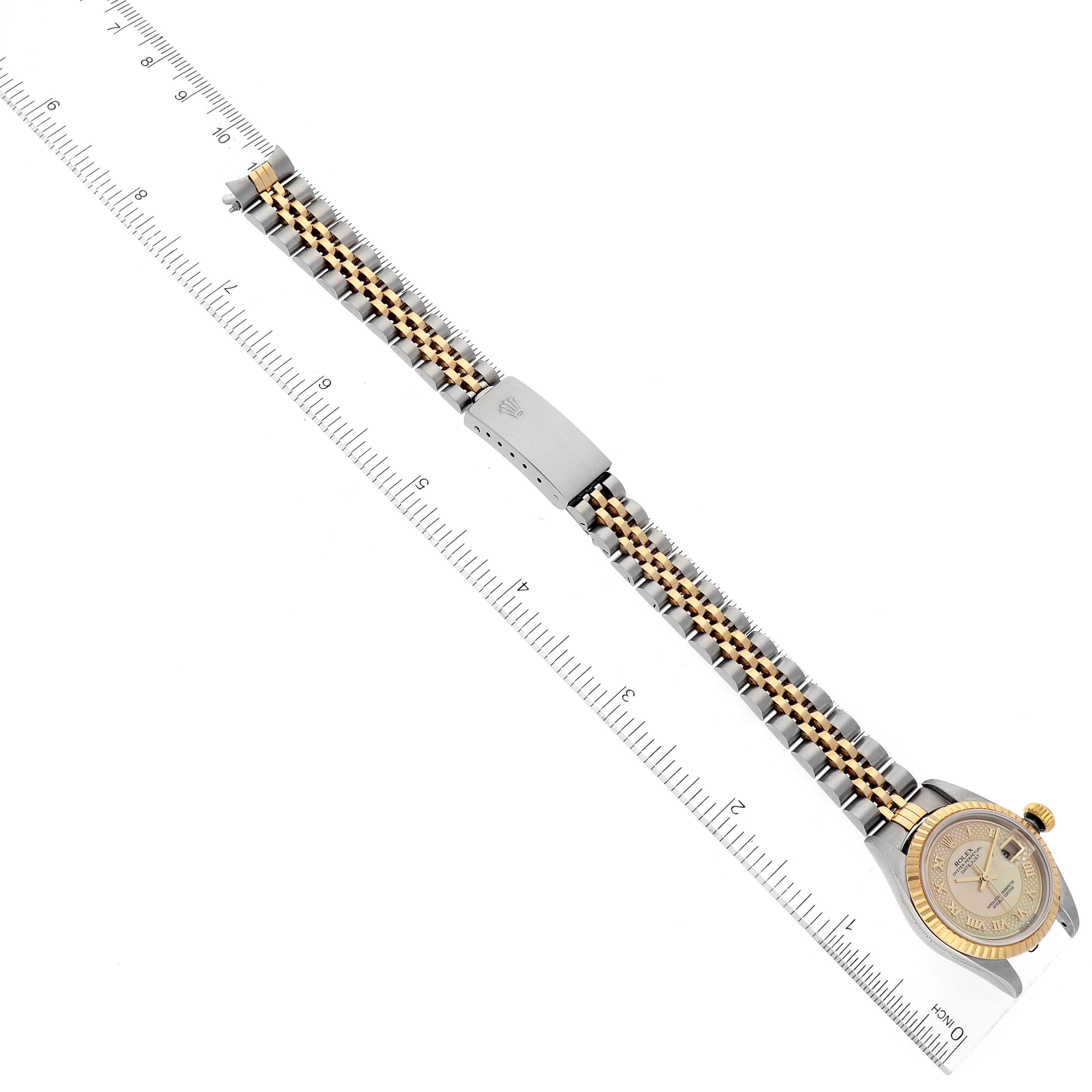The Rolex Datejust 79173 Women's Steel and Gold (two tone) Mother of Pearl Dial 79173 Women's Steel and Gold (two tone) Mother of Pearl Dial watch is shown from an overhead angle, featuring its entire band and clasp against a ruler for scale.