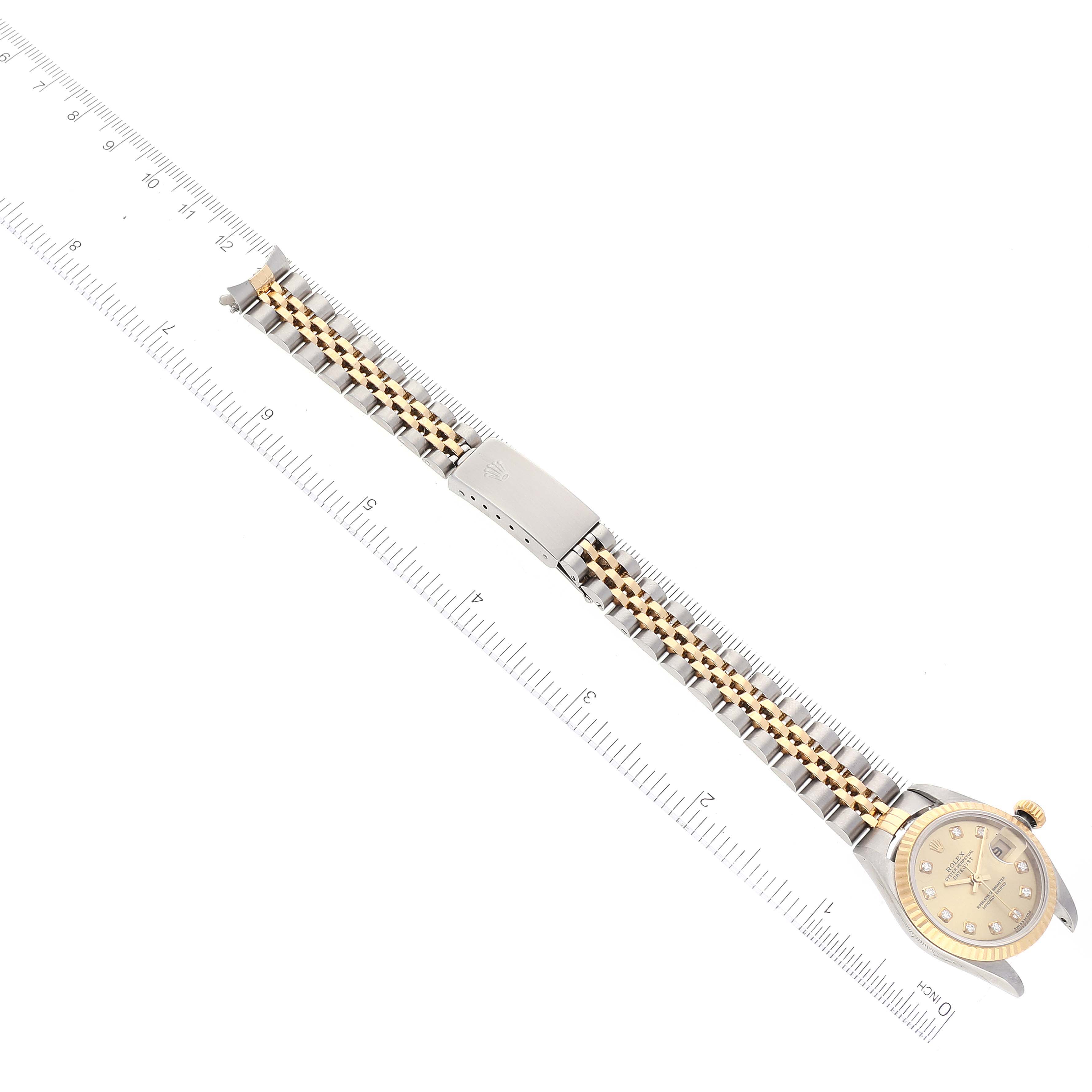 The image shows a Rolex Datejust 79173 Women's Steel and Gold (two tone) Champagne Dial 79173 Women's Steel and Gold (two tone) Champagne Dial watch laid flat, highlighting its face, bracelet, and clasp, next to a ruler for scale.