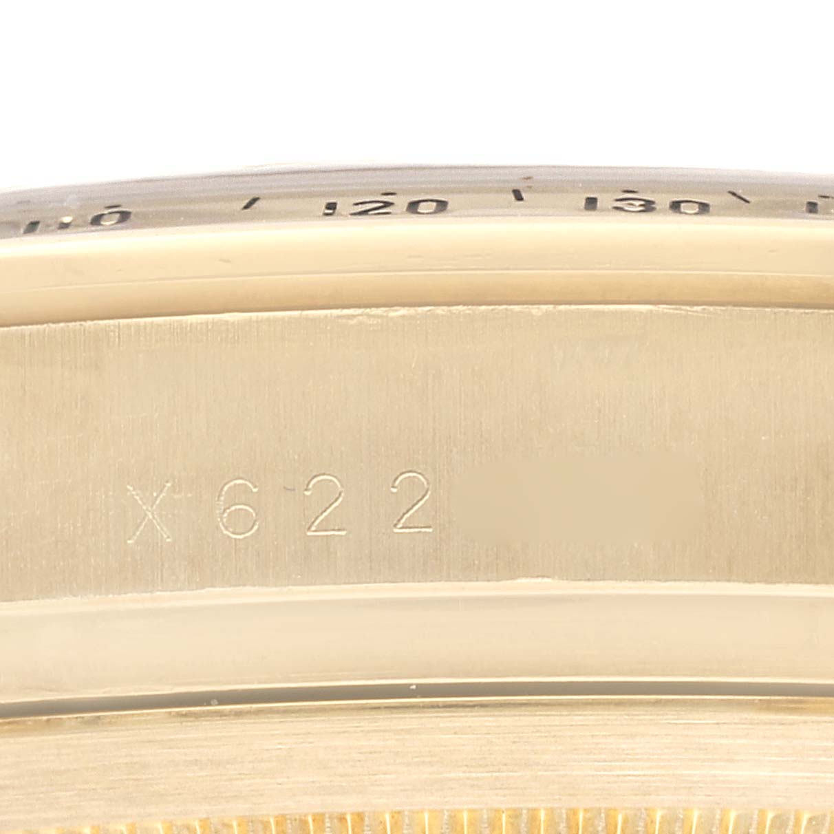 This close-up image shows the side case and part of the bezel, with a serial number, of a Rolex Daytona 16528 Men's Yellow Gold Black Dial 16528 Men's Yellow Gold Black Dial watch.