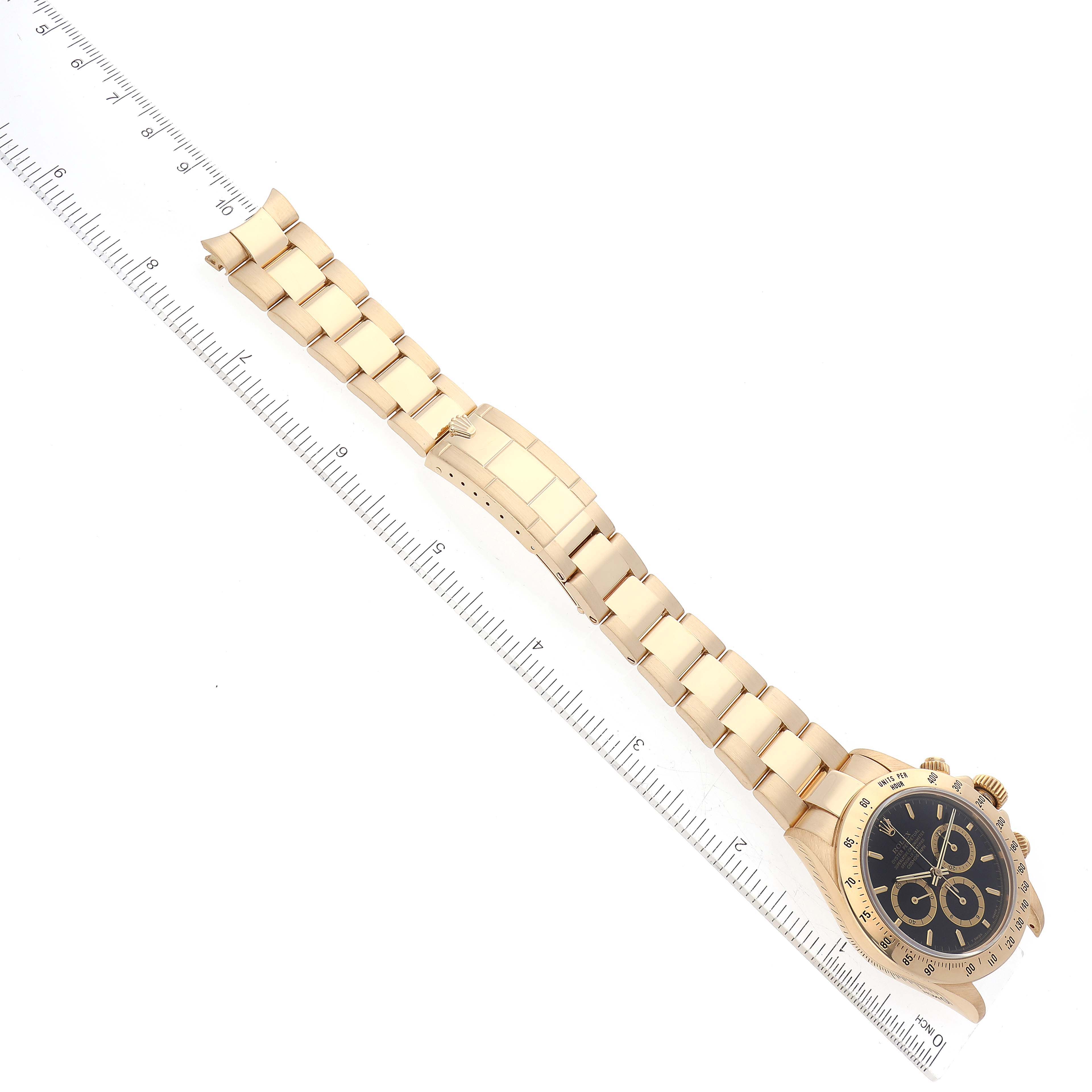 The image shows a top-down view of a Rolex Daytona 16528 Men's Yellow Gold Black Dial 16528 Men's Yellow Gold Black Dial watch, focusing on the face, band, and clasp with a ruler alongside for scale.