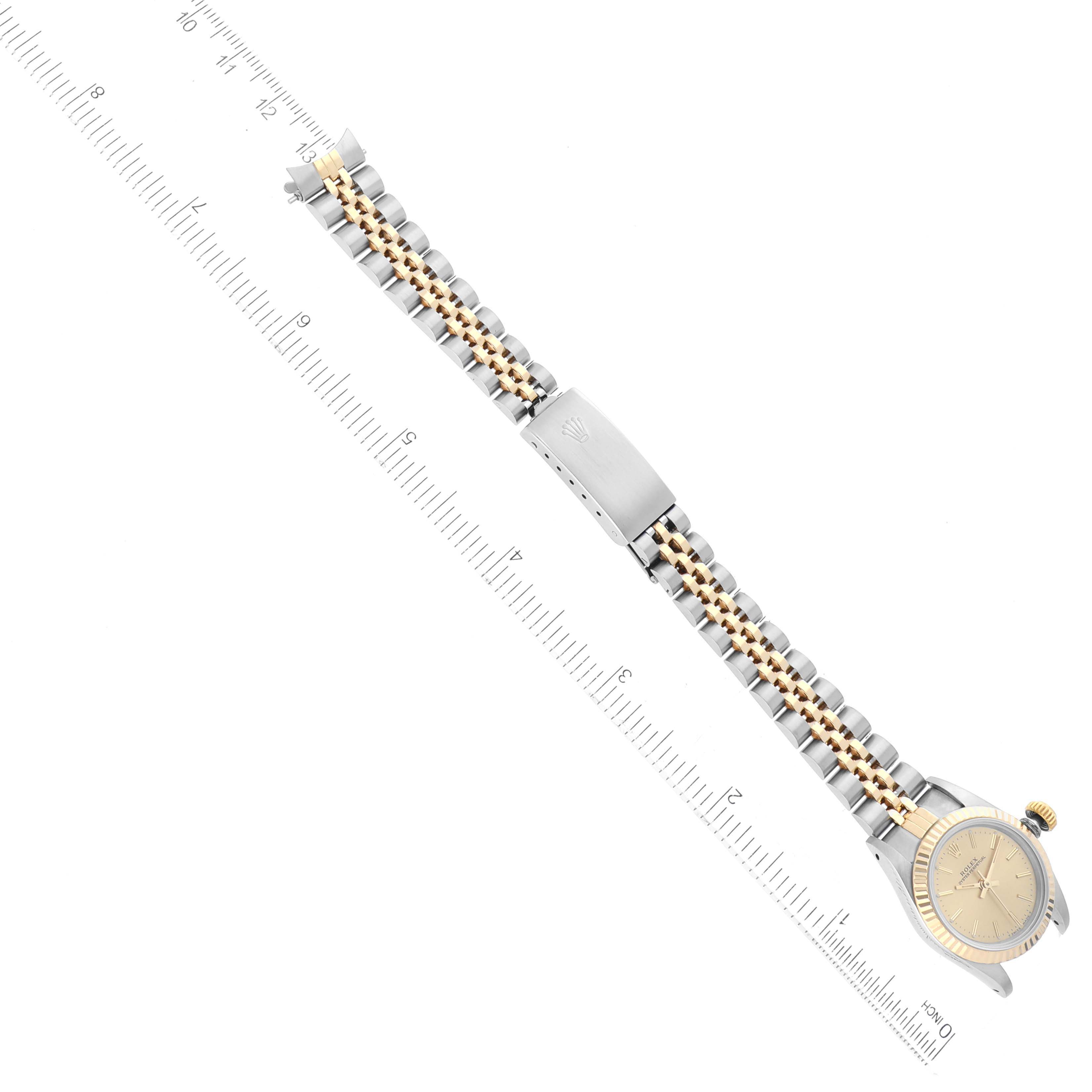 The image shows a top view of a Rolex Oyster Perpetual 67193 Women's Steel and Gold (two tone) Champagne Dial 67193 Women's Steel and Gold (two tone) Champagne Dial watch emphasizing the bracelet and clasp with a ruler for scale.