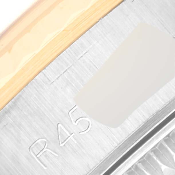 This close-up image captures part of the bezel and case with the "R45" marking of a Rolex Oyster Perpetual 67193 Women's Steel and Gold (two tone) Champagne Dial 67193 Women's Steel and Gold (two tone) Champagne Dial watch.