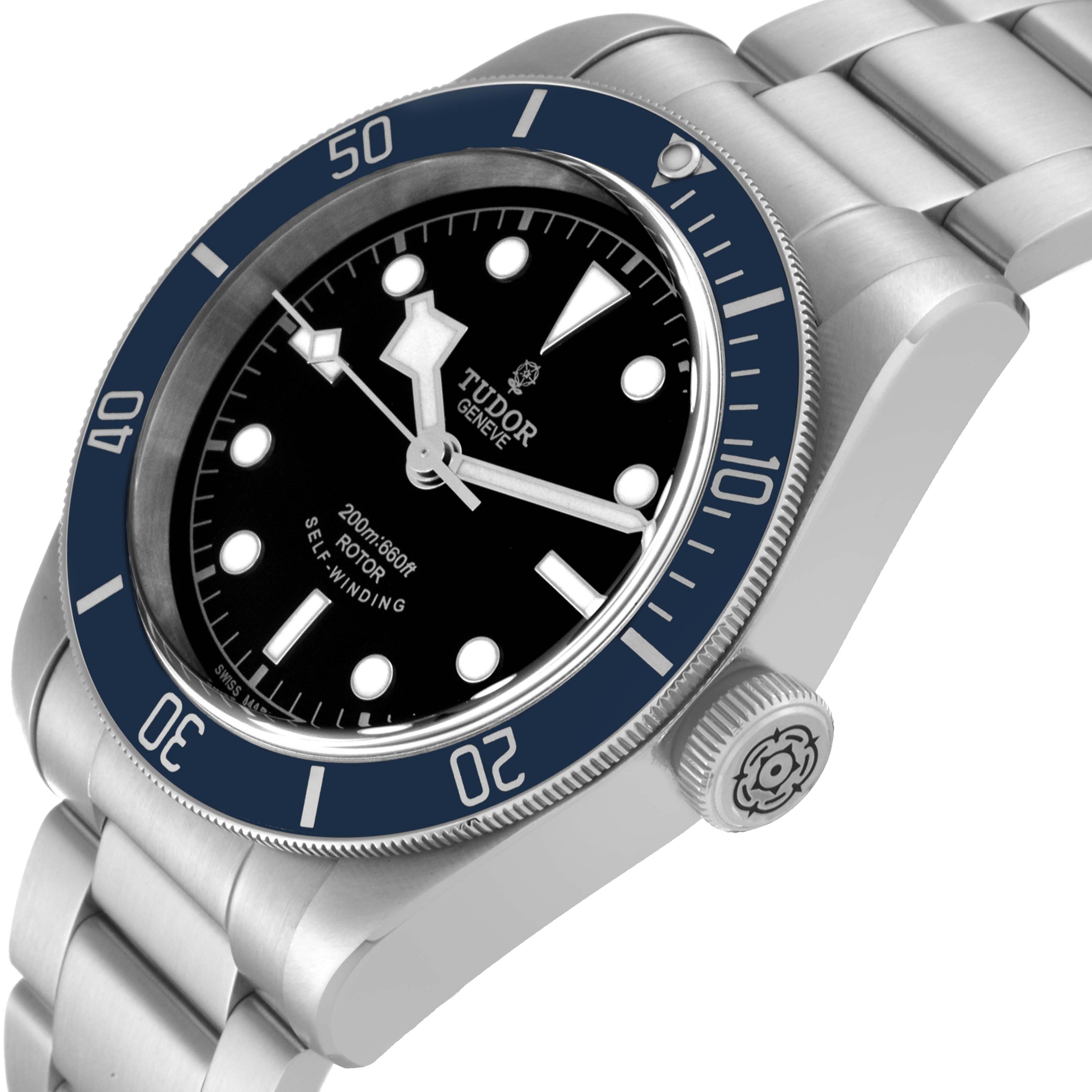 The image shows a tilted angle of the Tudor Heritage Black Bay 79220B Men
s Stainless Steel Black Dial 79220B Men
s Stainless Steel Black Dial watch, highlighting the dial, bezel, crown, and bracelet.