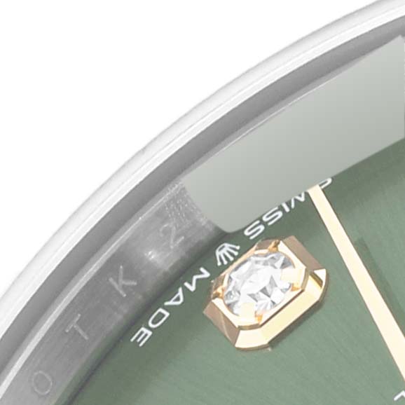 This close-up image shows the bezel, part of the green dial, a diamond marker, and "Swiss Made" text of the Mid-Size Rolex watch.
